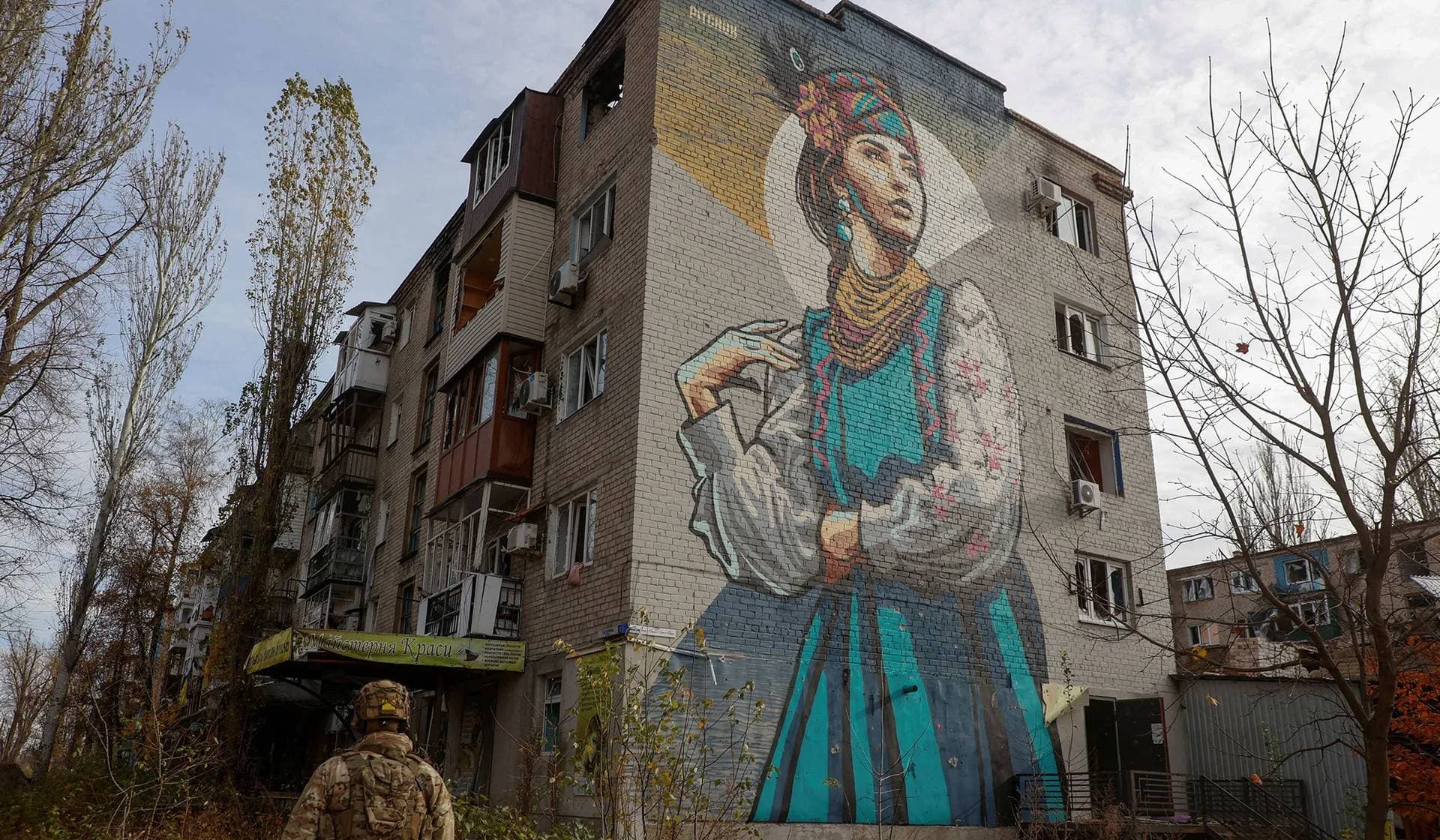 A Ukrainian serviceman walks next to a residential building in Avdiivka