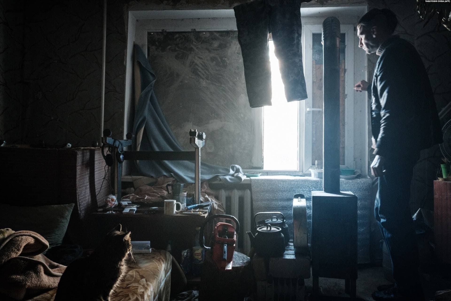 Oleksandr Luhovskykh stares out the window in the stove-heated room where he lives