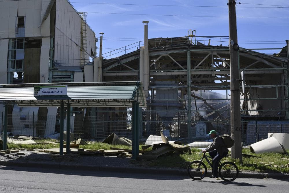 A man rides a bicycle past a building damaged by Russian shelling in Bakhmut