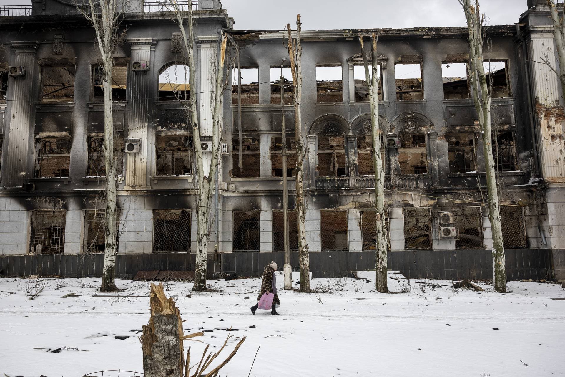 A local resident carries humanitarian aid while passing through a battle-scarred downtown area of Bakhmut