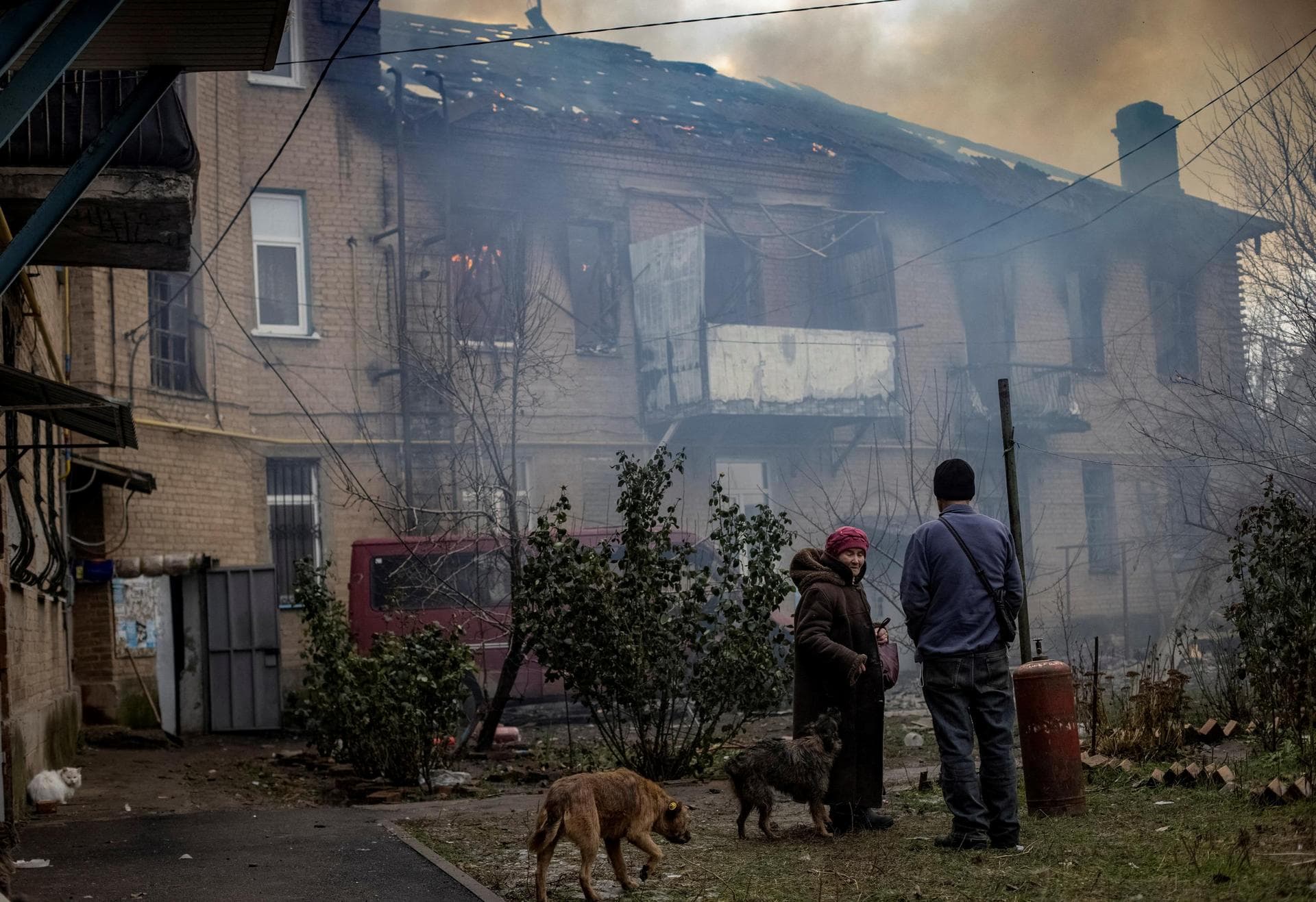 Local residents stand in the yard of their destroyed apartment building in Bakhmut