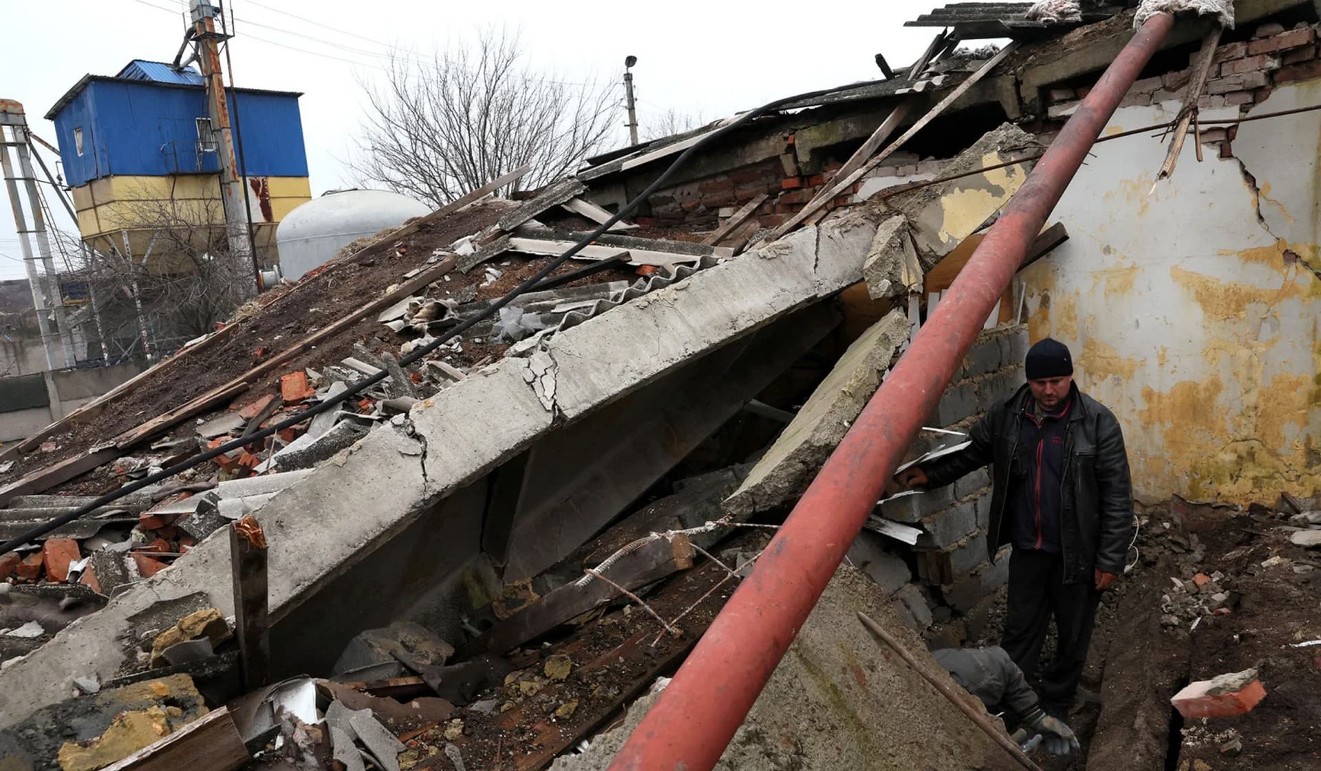 Workers dig out a tractor tire from the rubble of a destroyed storage building at a grain processing center in Siversk