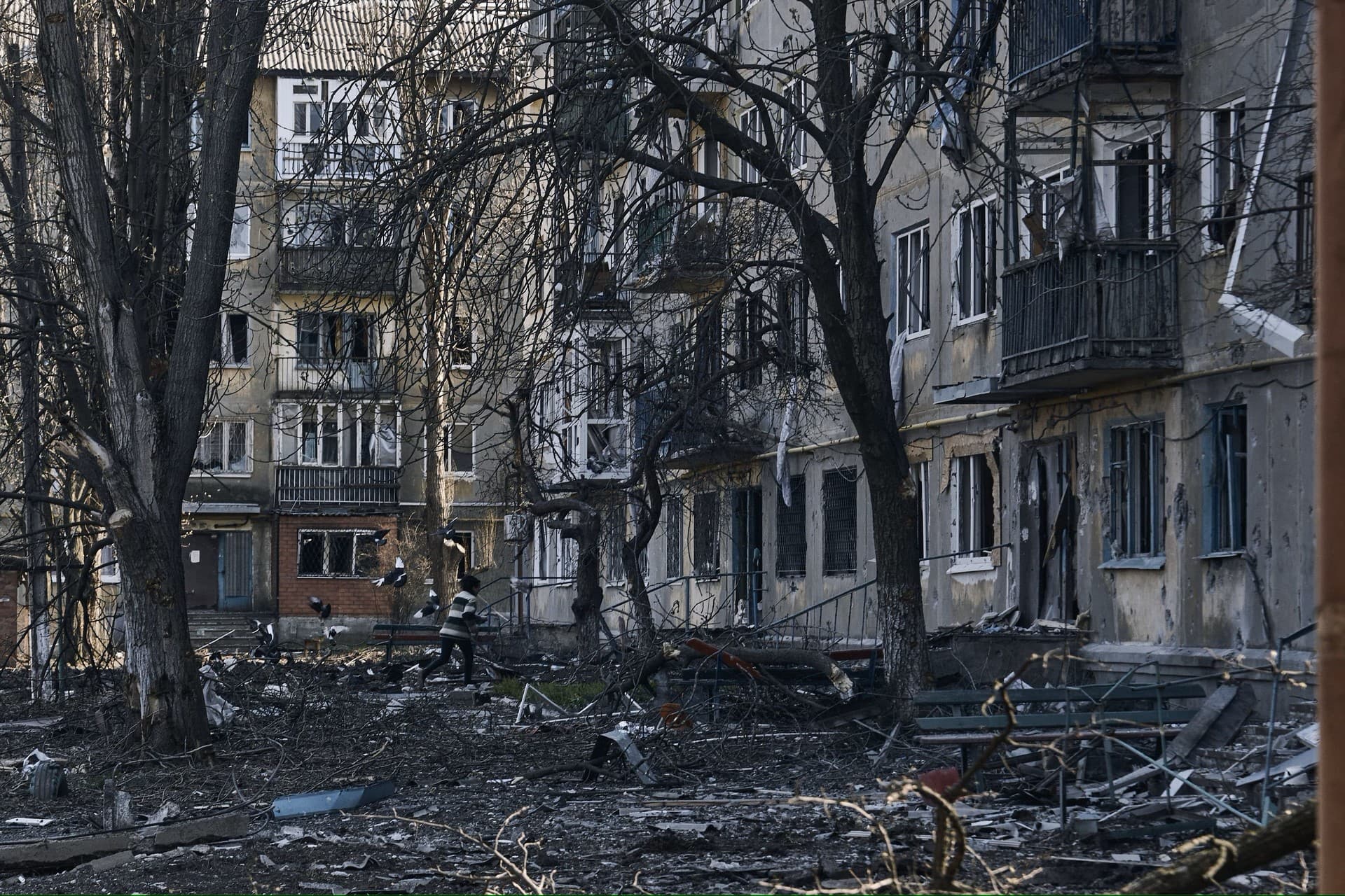A local resident runs past the damaged houses in Bakhmut