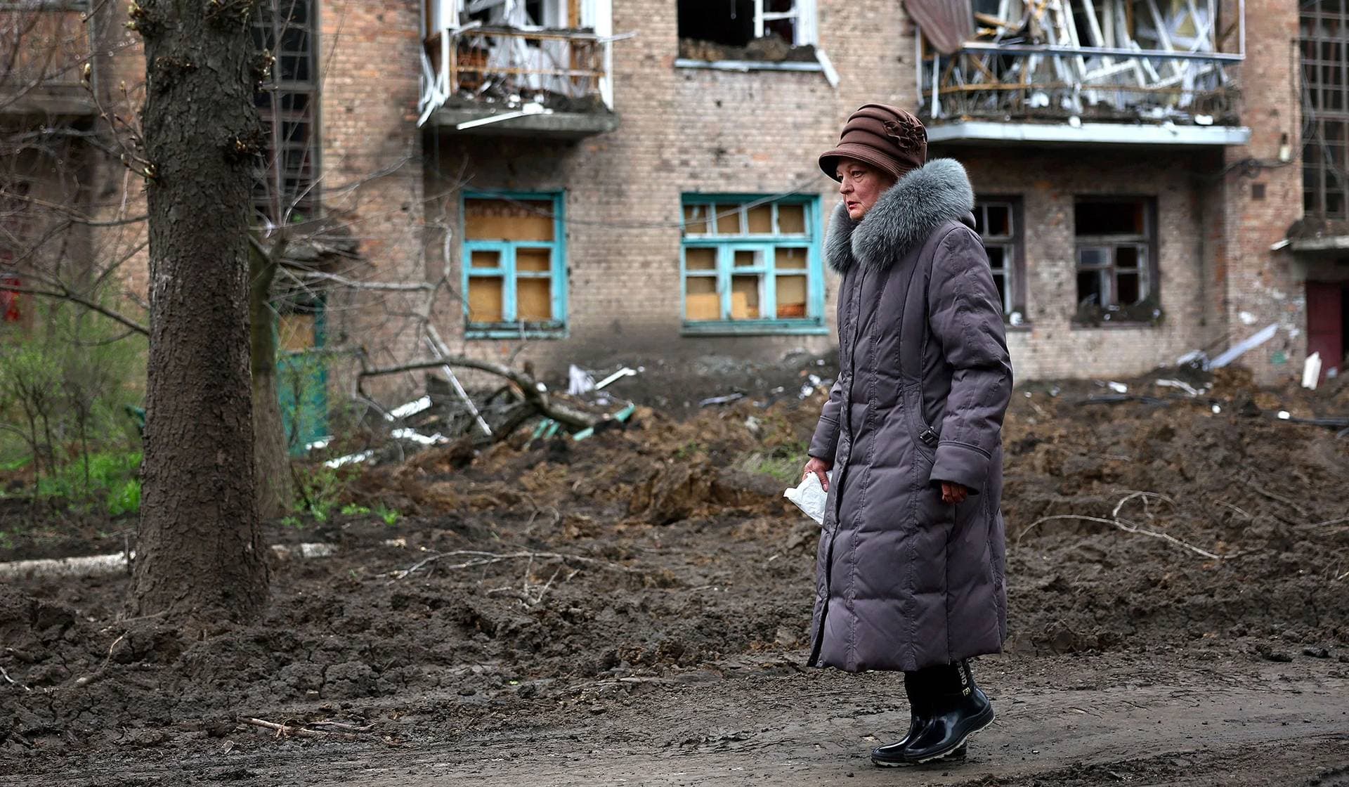 One of the few remaining villagers walks past a building damaged by recent shelling during heavy fighting at the frontline in Chasiv Yar