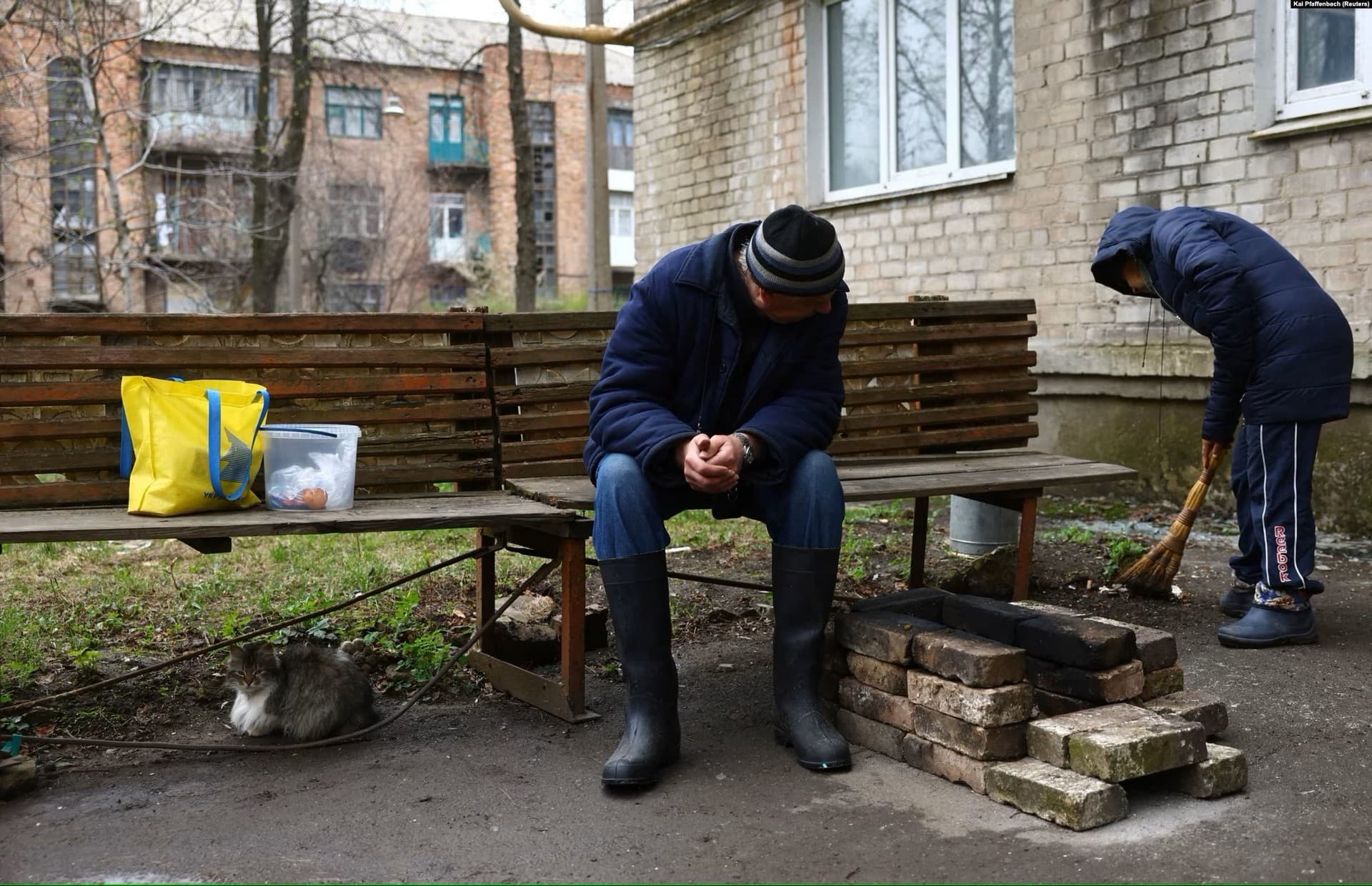 Civilians in Chasiv Yar clean near an improvised fireplace during a lull in shelling