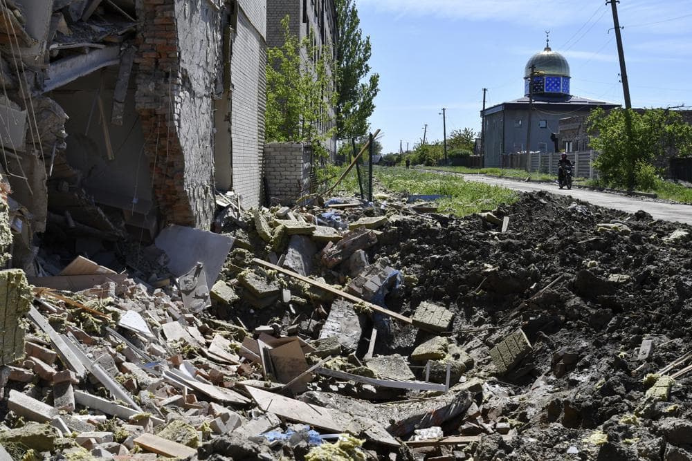 A crater of an explosion after Russian shelling is seen next to a damaged apartment building in Bakhmut