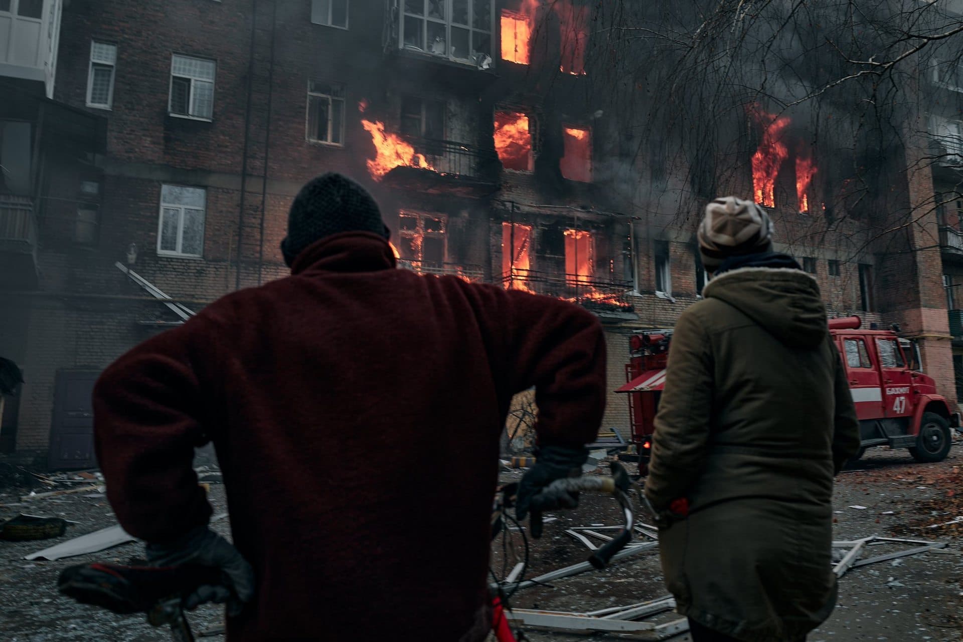 Local residents watch as their apartment burns following shelling