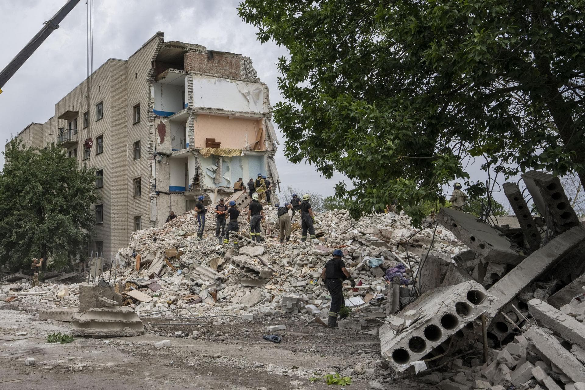Rescue workers stand on the rubble at the scene in the after math of a missile strike that his a residential apartment block, in Chasiv Yar, Donetsk region