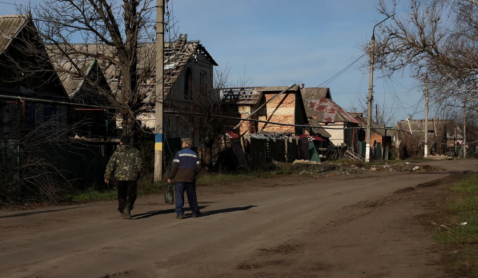 Two men walk home as the sounds of incoming and outgoing artillery fire fill the air in Siversk