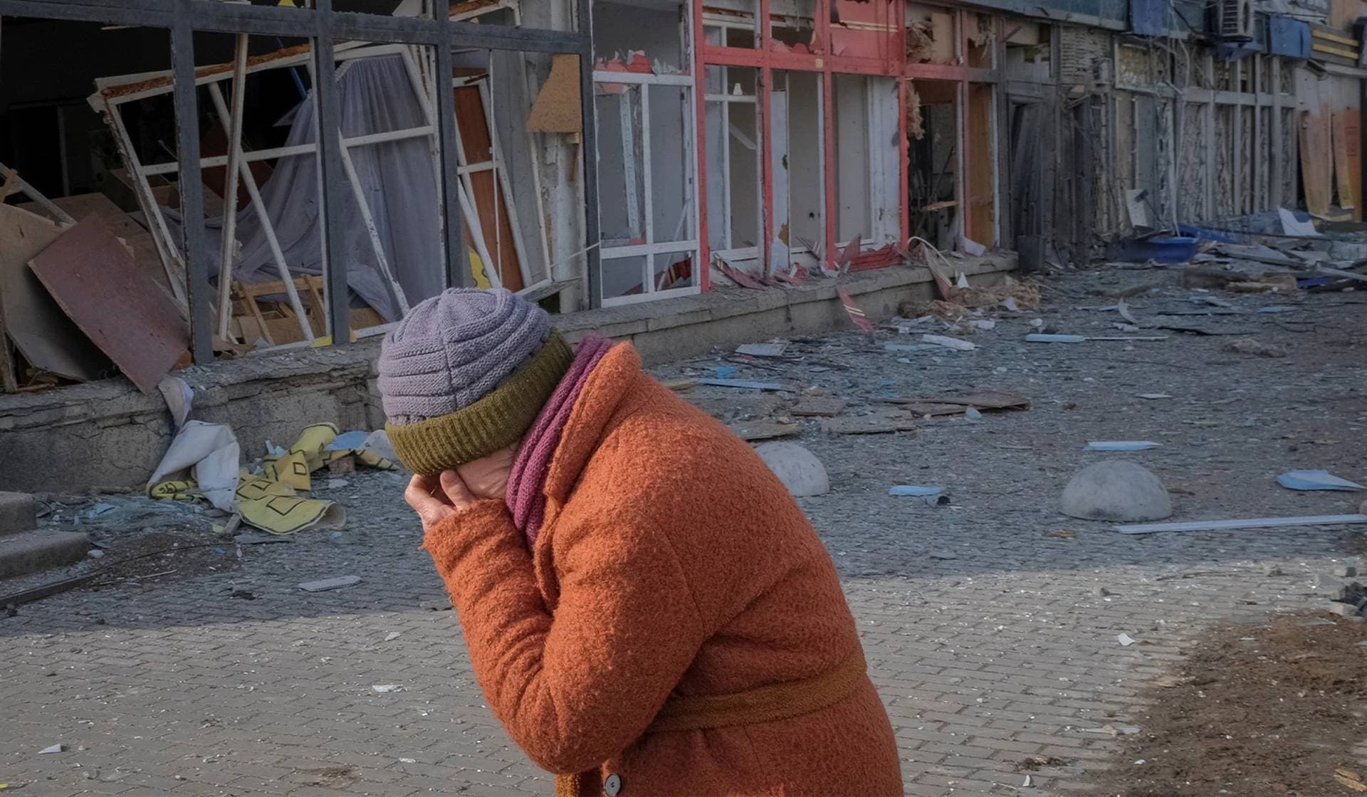 A local resident reacts as she walks down an empty street near a building damaged by a Russian military strike in the front line city of Bakhmut