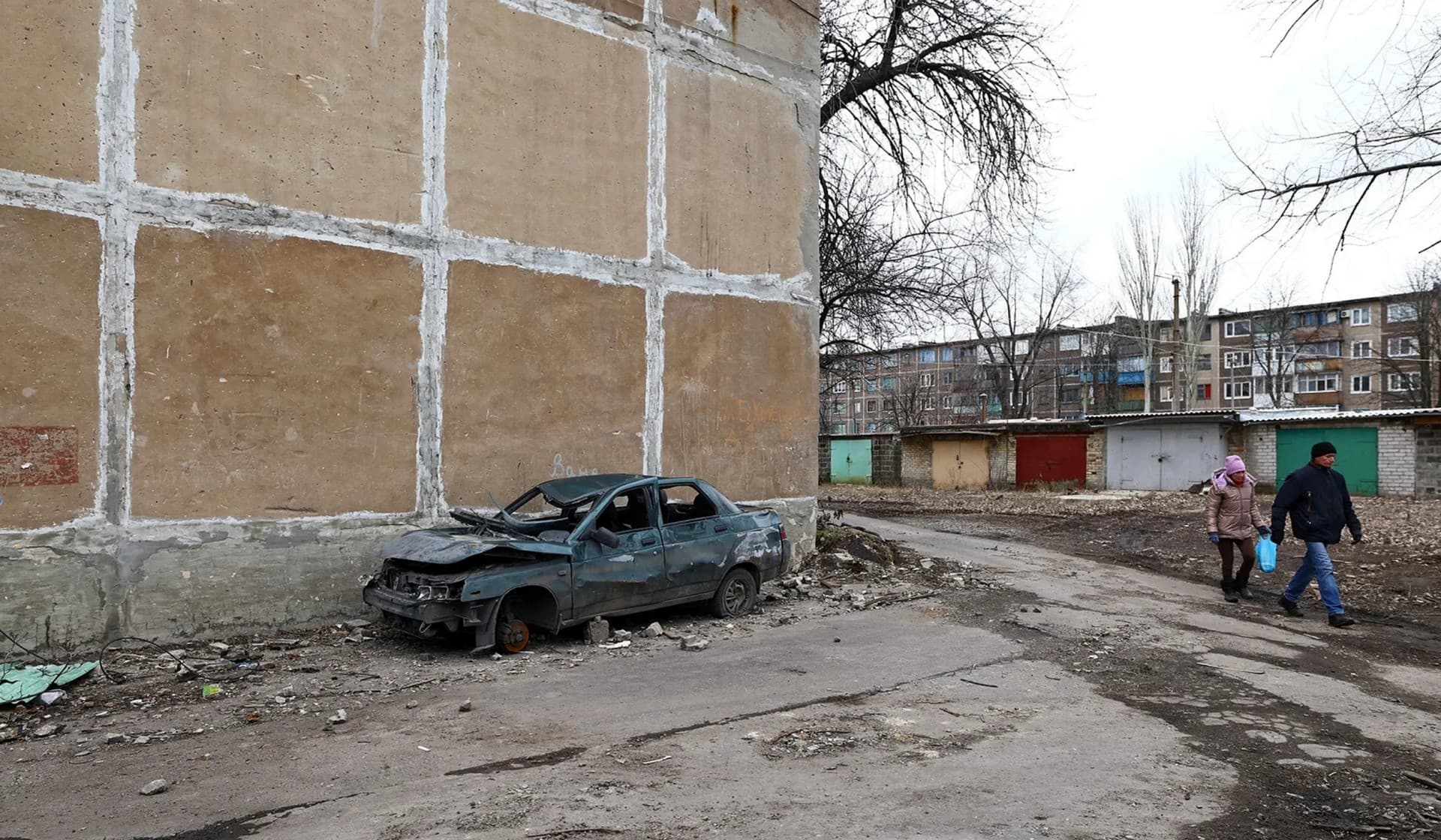 People walk along a path next to residential buildings in Chasiv Yar