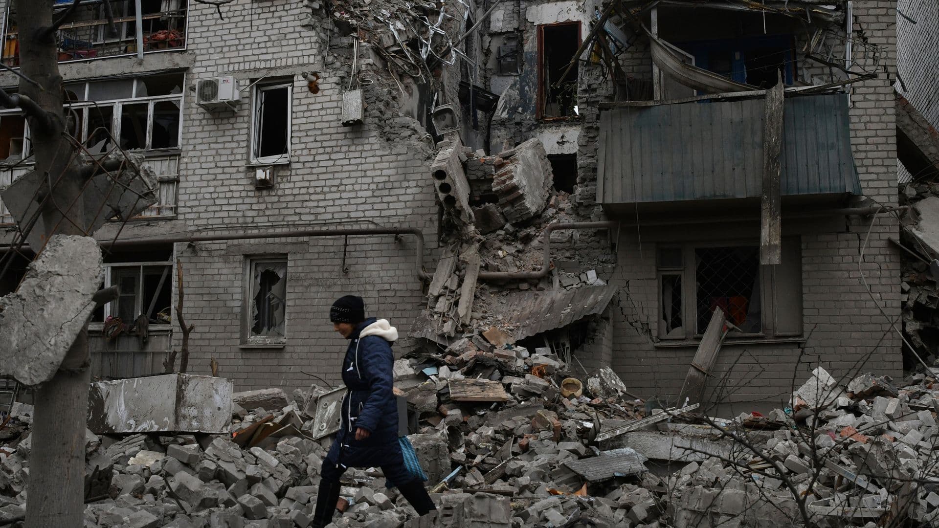 A woman walks past the debris of the destroyed house after a recent Russian air strike in Chasiv Yar