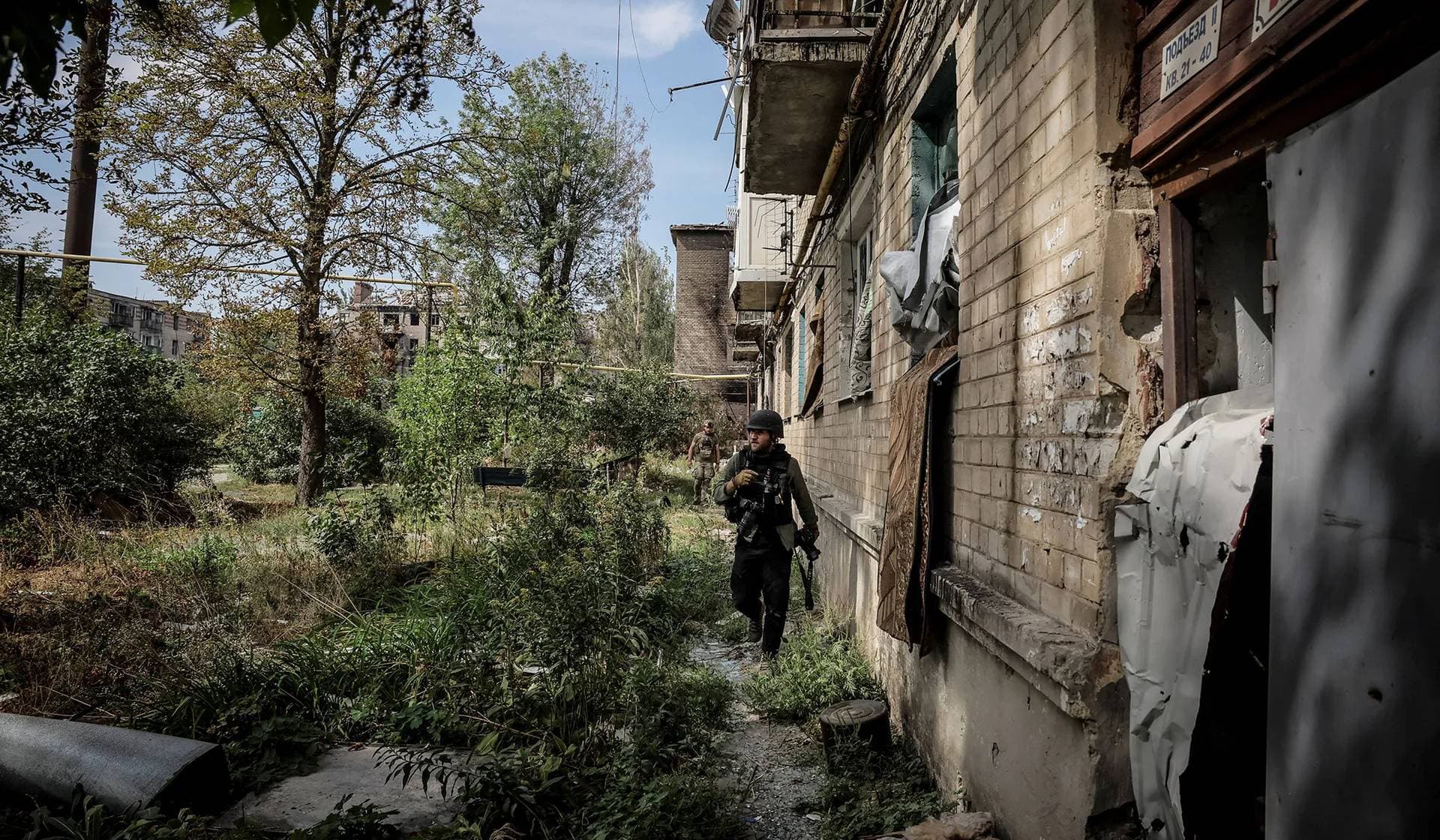 A journalist walks near residential buildings heavily damaged during a Russian military attack, in the frontline town of Chasiv Yar
