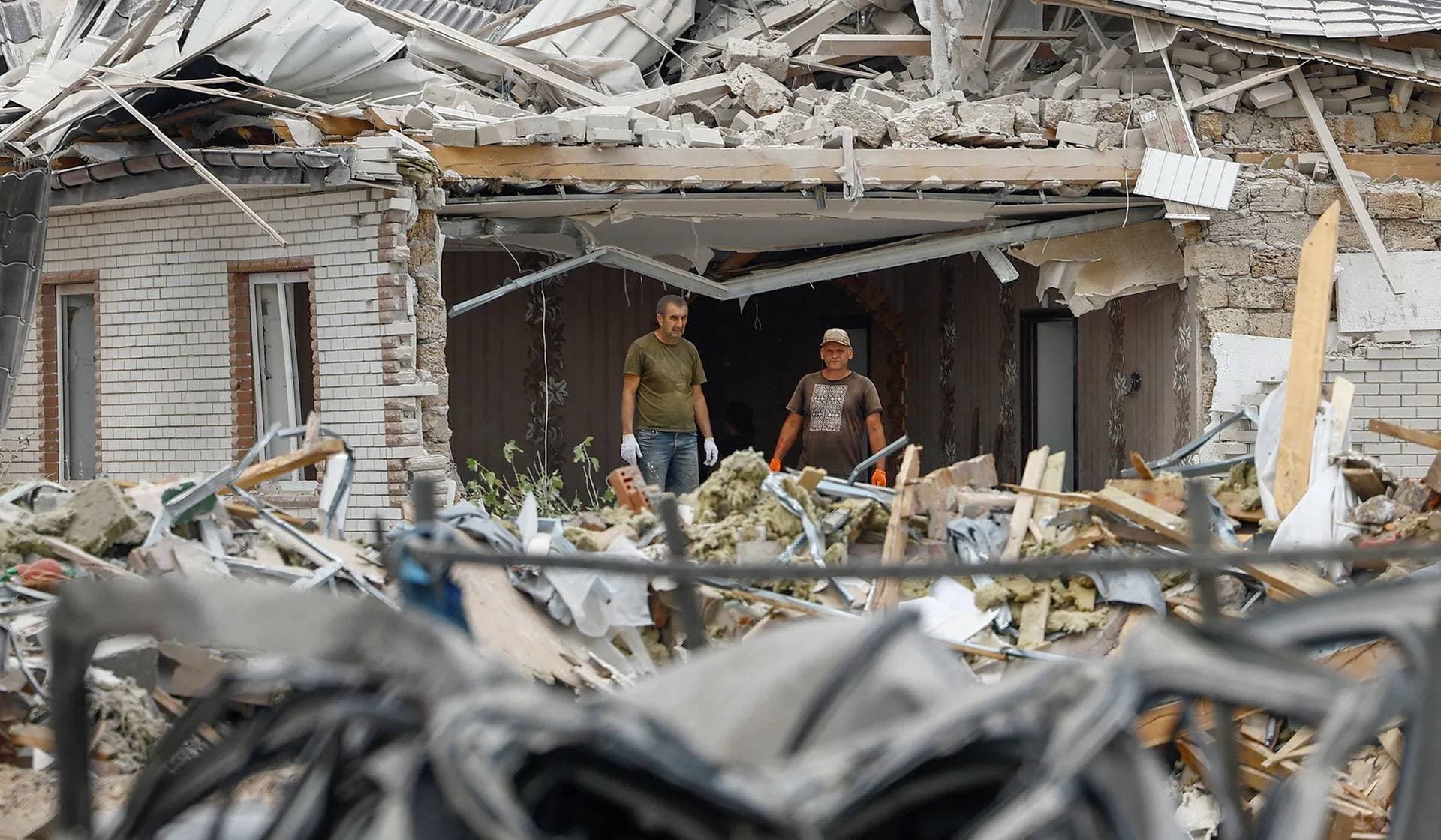Local men stand stand inside a residential building heavily damaged during a Russian missile strike in Rozhivka