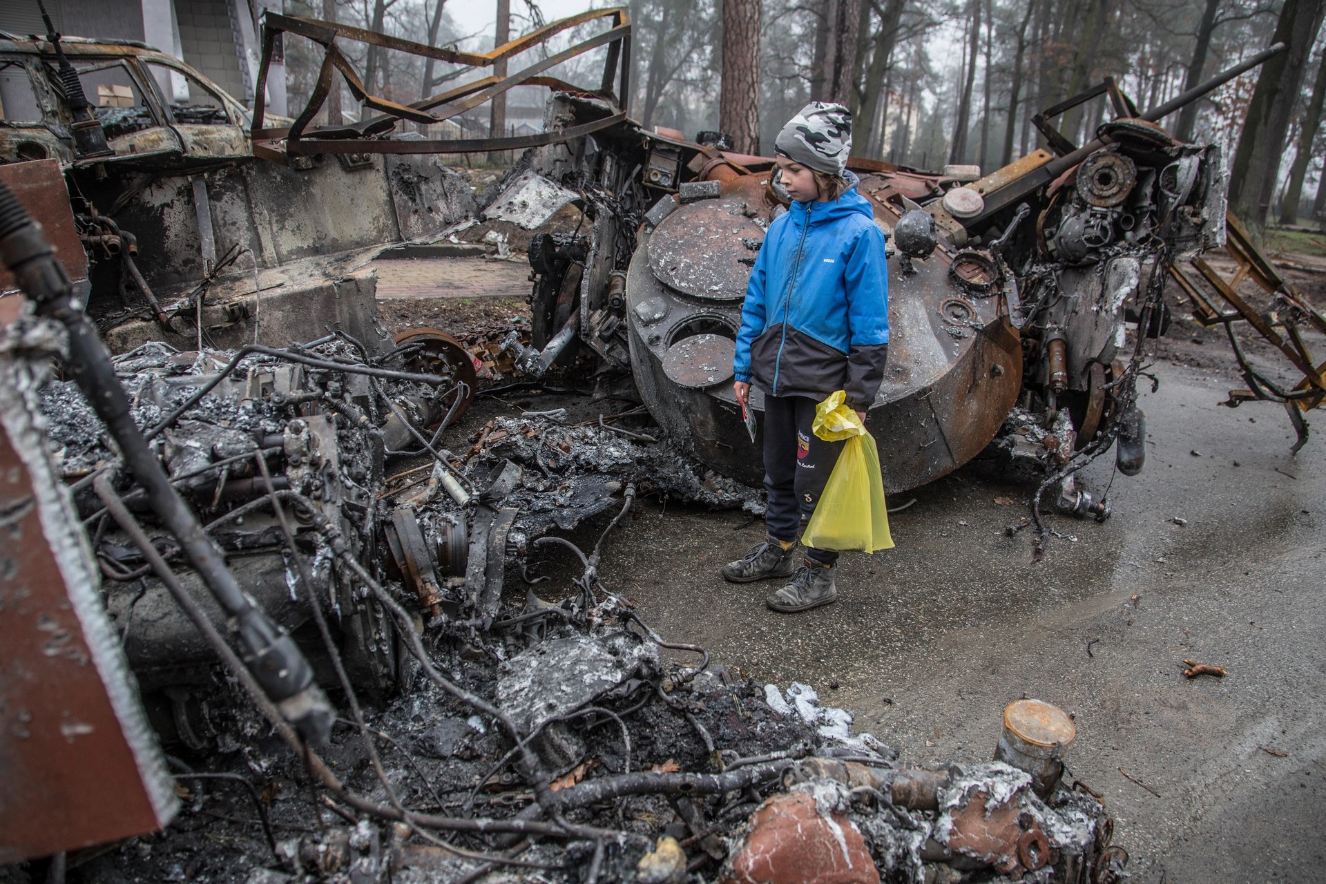 A boy looks at a destroyed Russian tank in Bucha