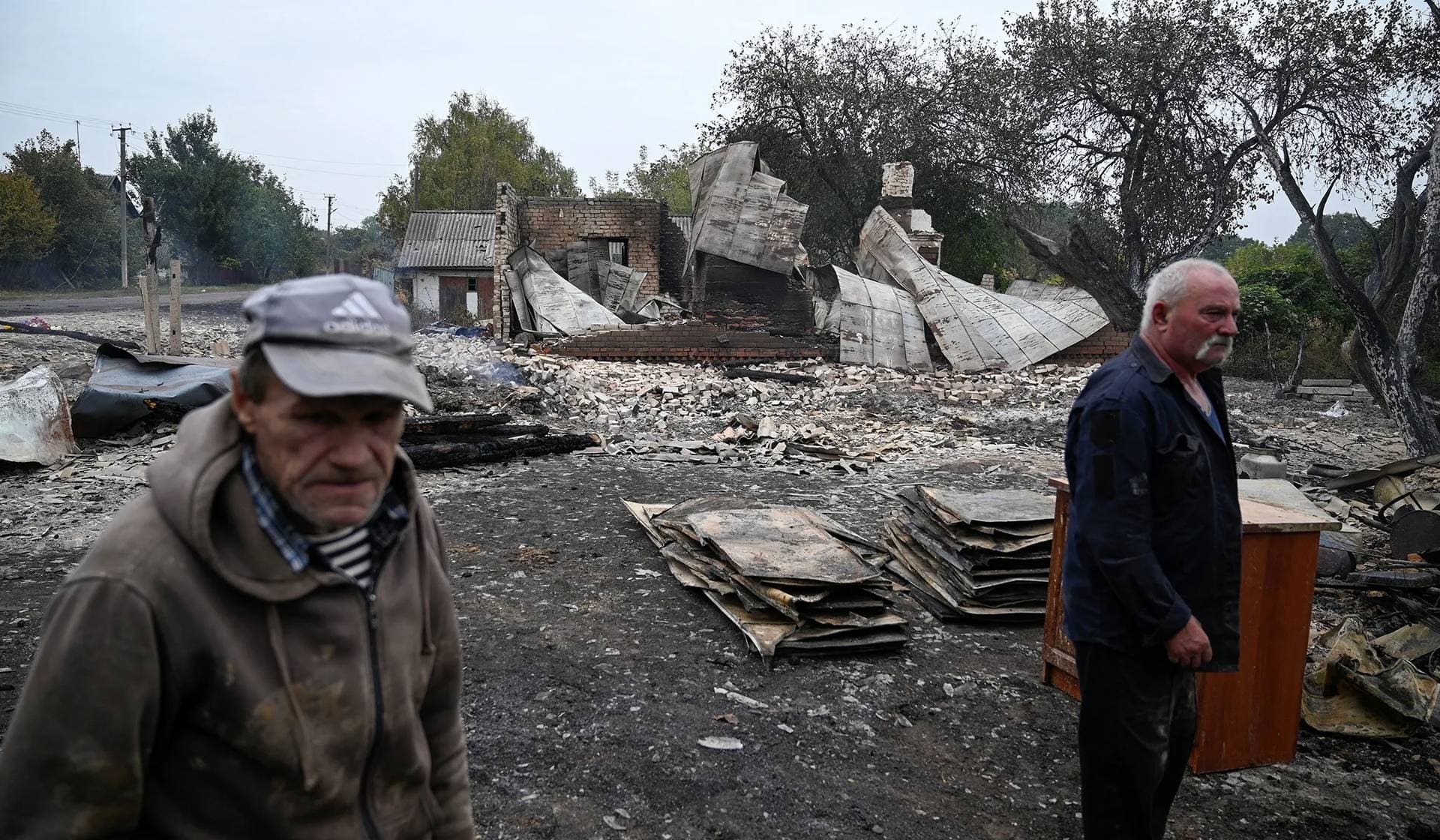 Men stand near a building heavily damaged during a Russian military strike in Hirske