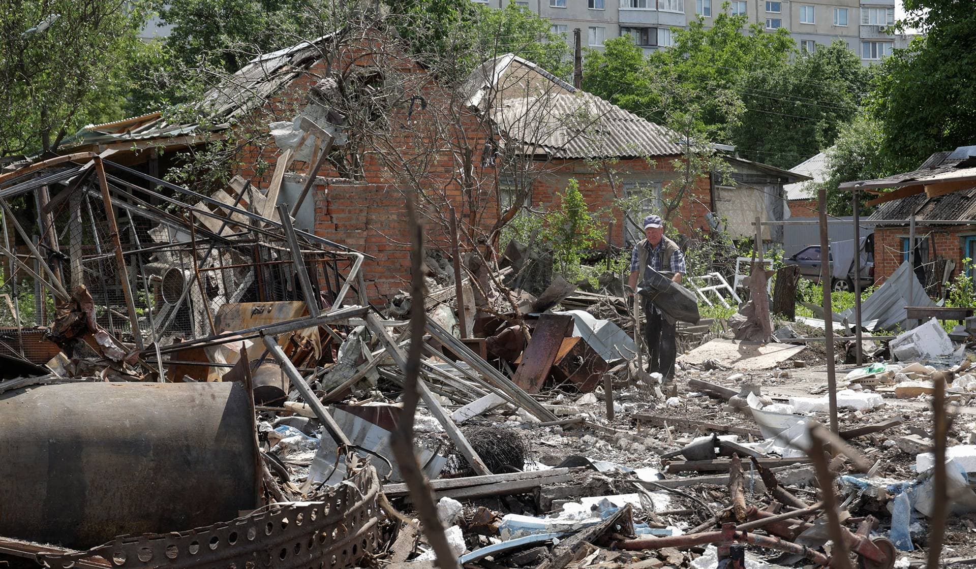 A man removes debris in the backyard of his house damaged during overnight Russian drone strikes in the town of Chuhuiv