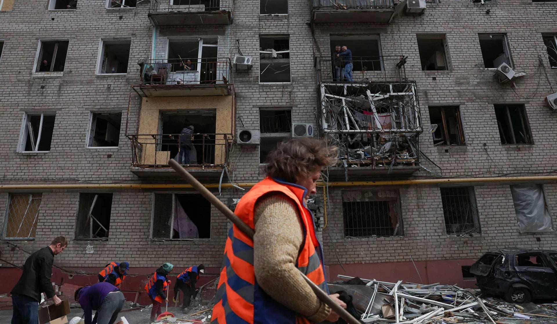 A worker taking part in cleaning operations walks past an apartment block damaged during an overnight Russian drone strike in Dnipro