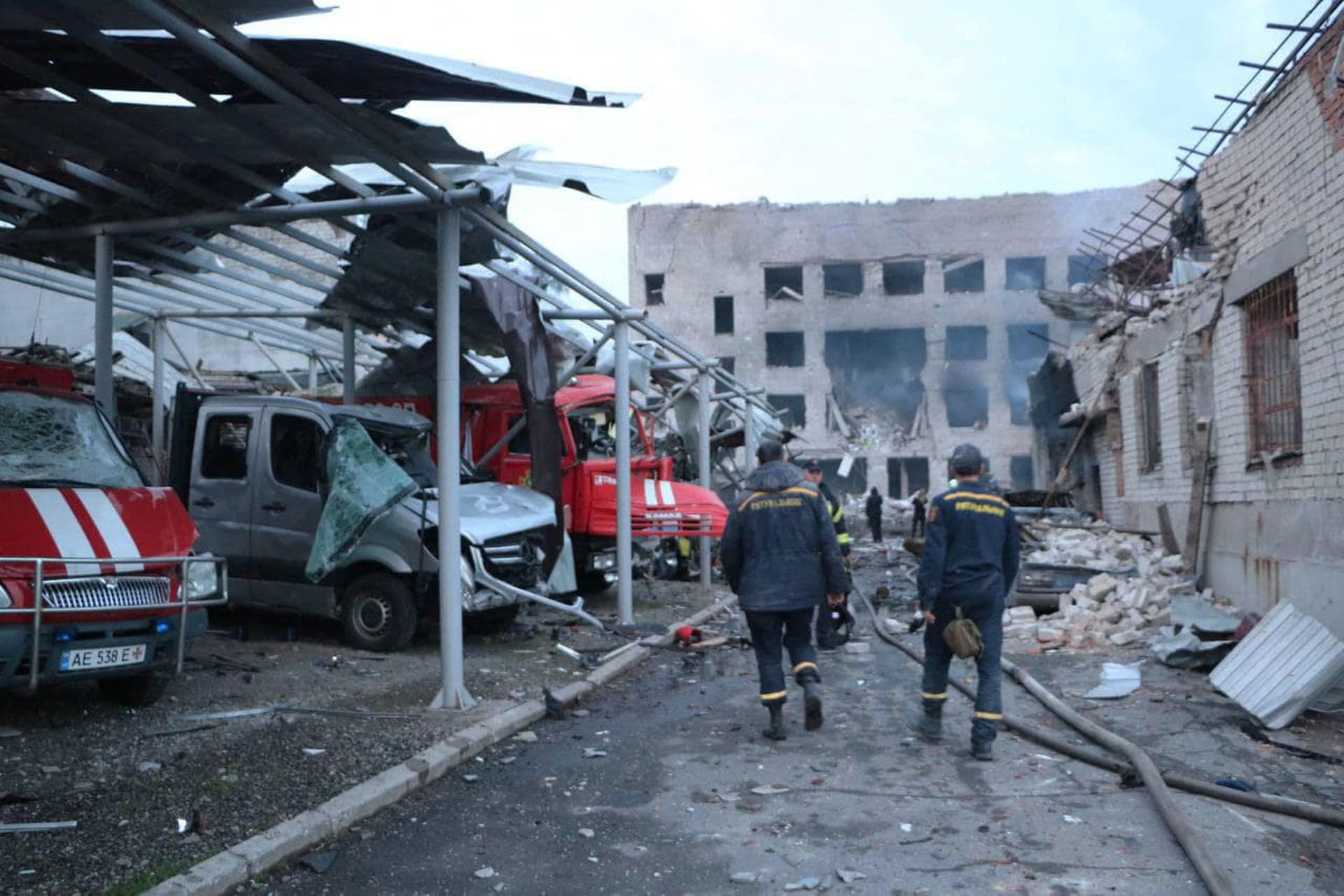 Rescuers walk past destroyed vehicles at a fire depot of the State Emergency Service heavily damaged by a Russian missile strike in Dnipro