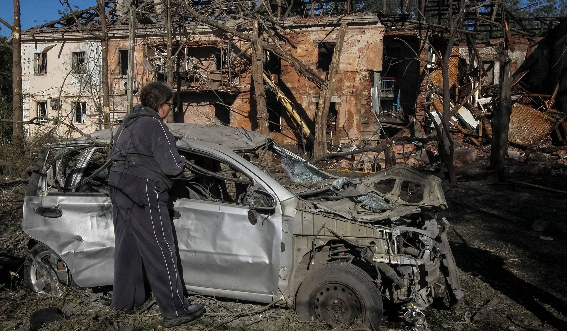 A resident inspects a destroyed car at a site of a Russian drone and missile strike in Dnipro