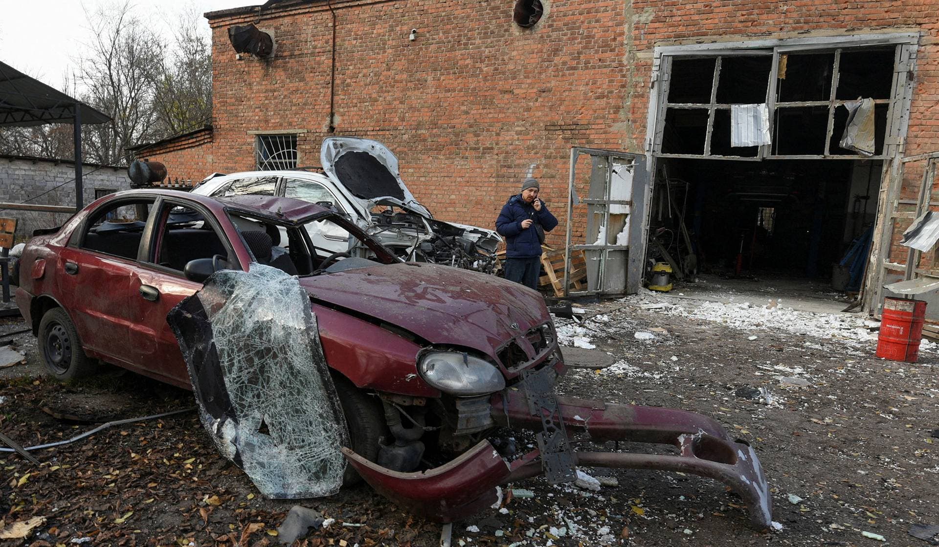 A resident speaks on his mobile phone at the compound of a car repair workshop damaged by a Russian drone strike in Dnipro