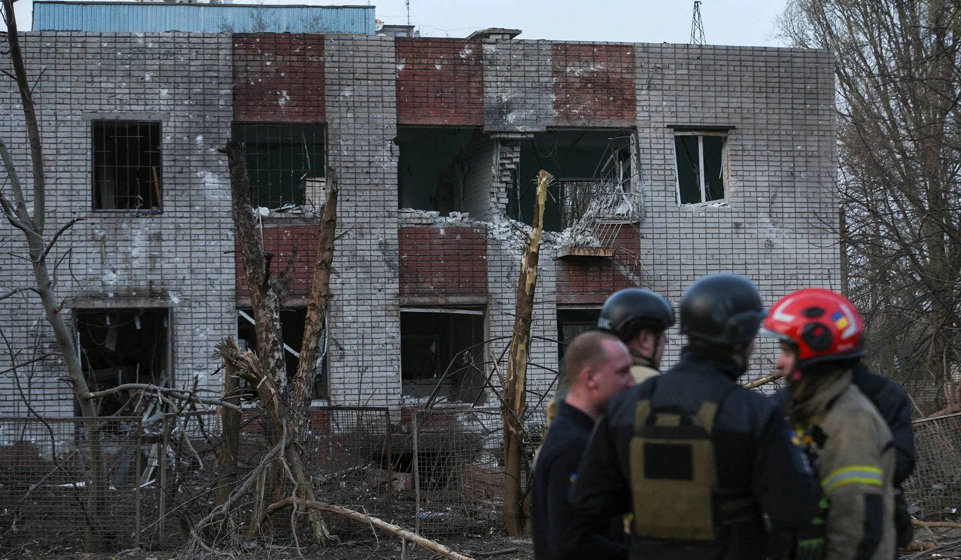 Emergency workers stand in a front of a building damaged during a Russian missile strike in Dnipro