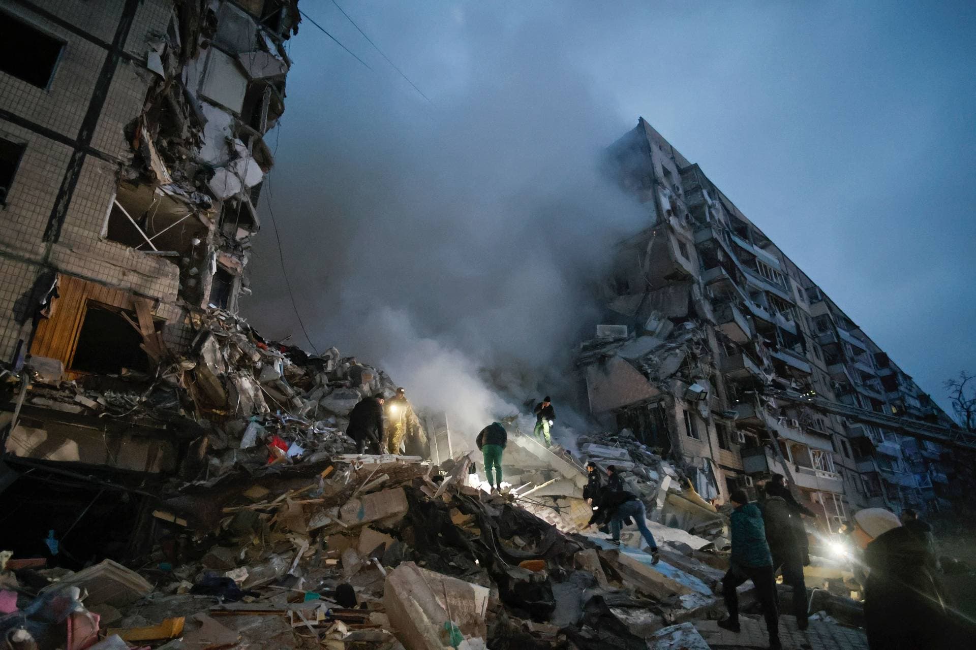 Local residents clear the rubble after a Russian rocket hit a multistory building leaving many people under debris in Dnipro