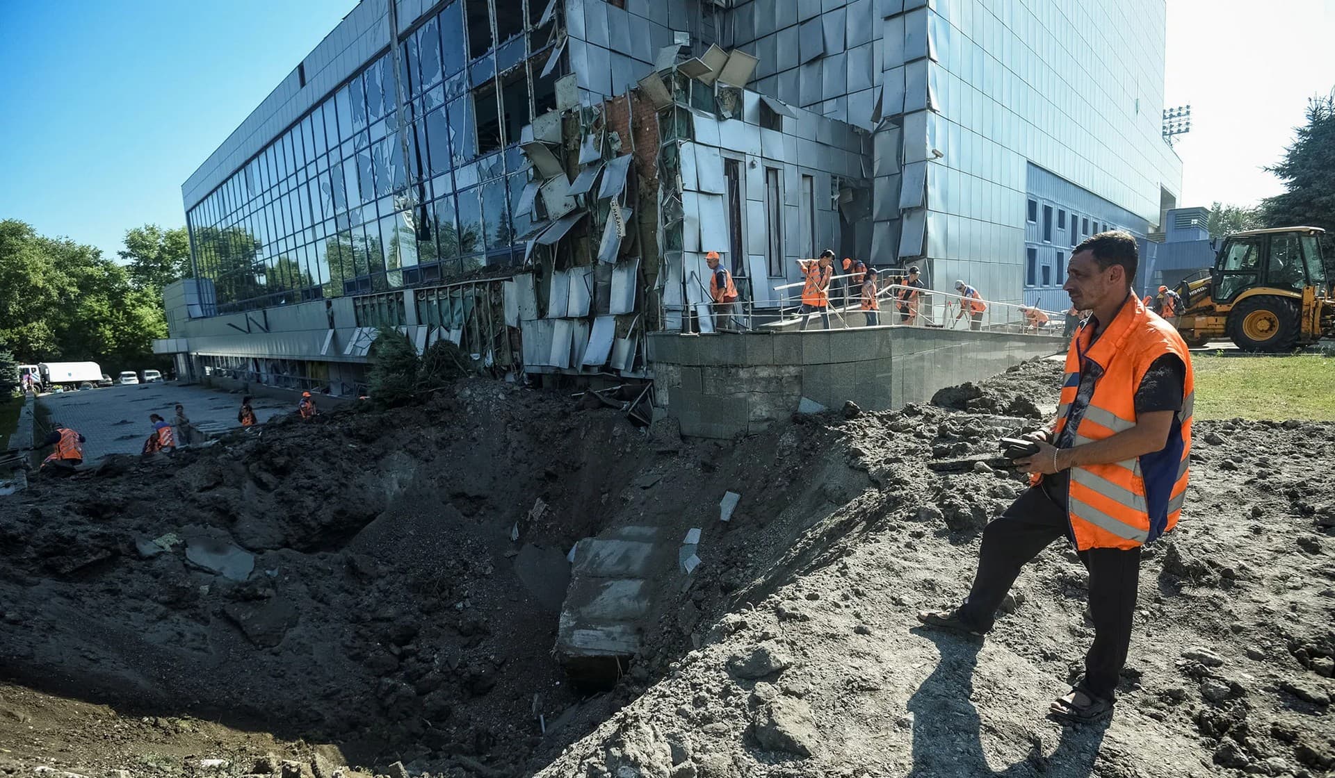 Communal workers clean an area at the site of a sports center destroyed during a Russian military strike in Dnipro