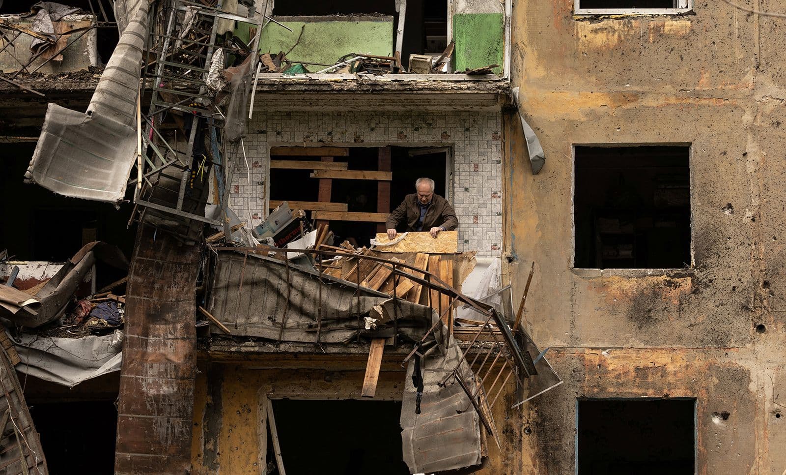 A man stands on the balcony of his apartment after a missile strike damaged a residential building in Ukraine's Donetsk region