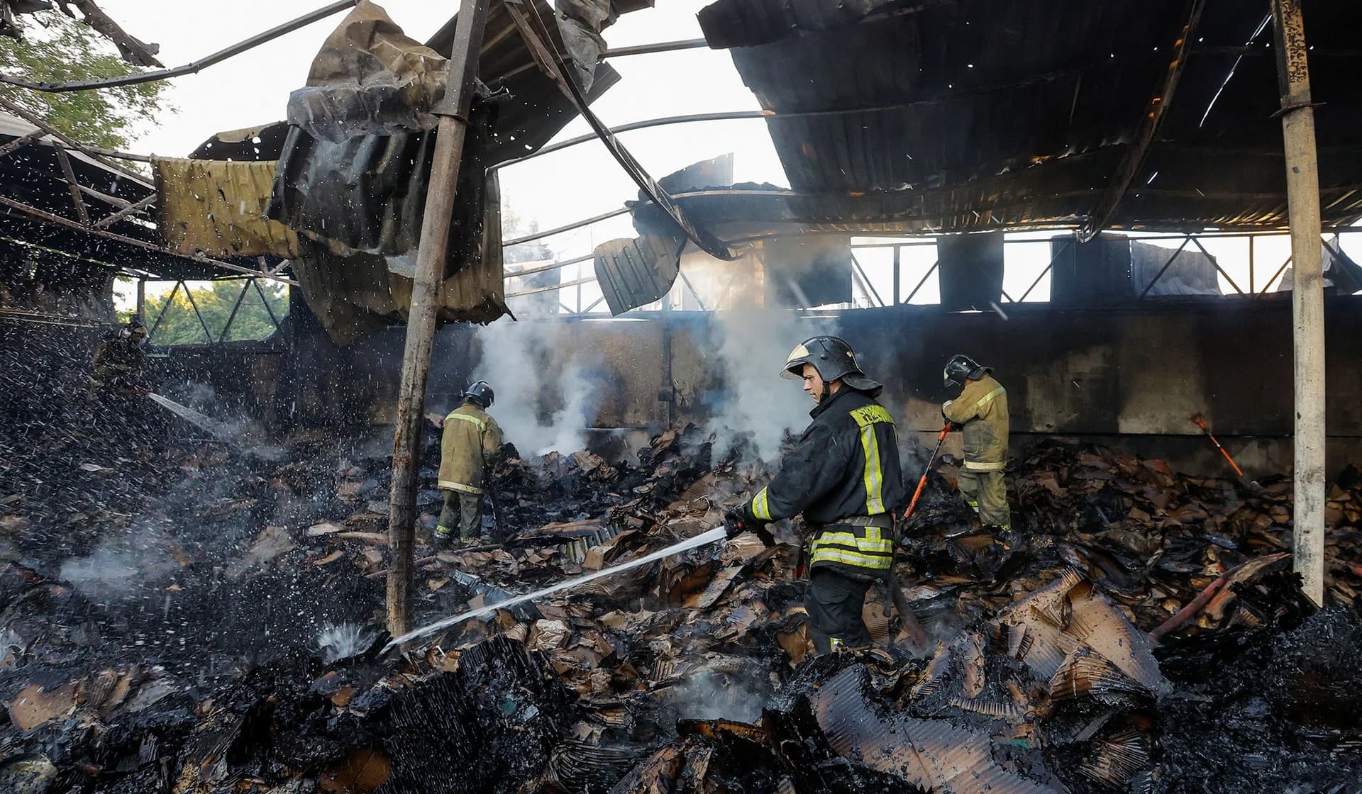 Firefighters work to extinguish fire at a warehouse destroyed in shelling in Donetsk