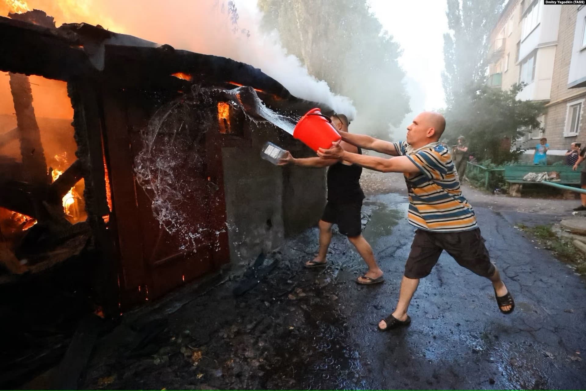 A man attempts to douse a fire with water after a strike on the Russian-held village of Lidiyevka