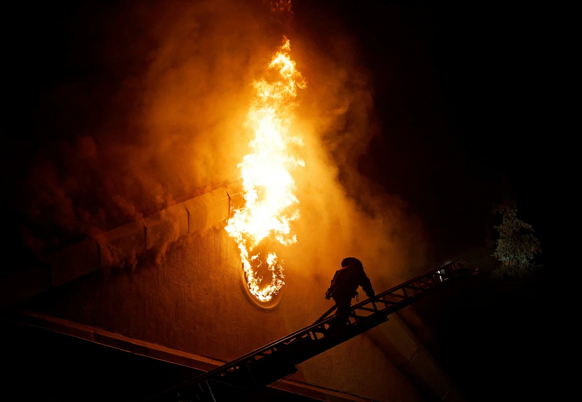 A firefighter climbs a ladder while extinguishing a fire in the university building following a reported shelling in Donetsk