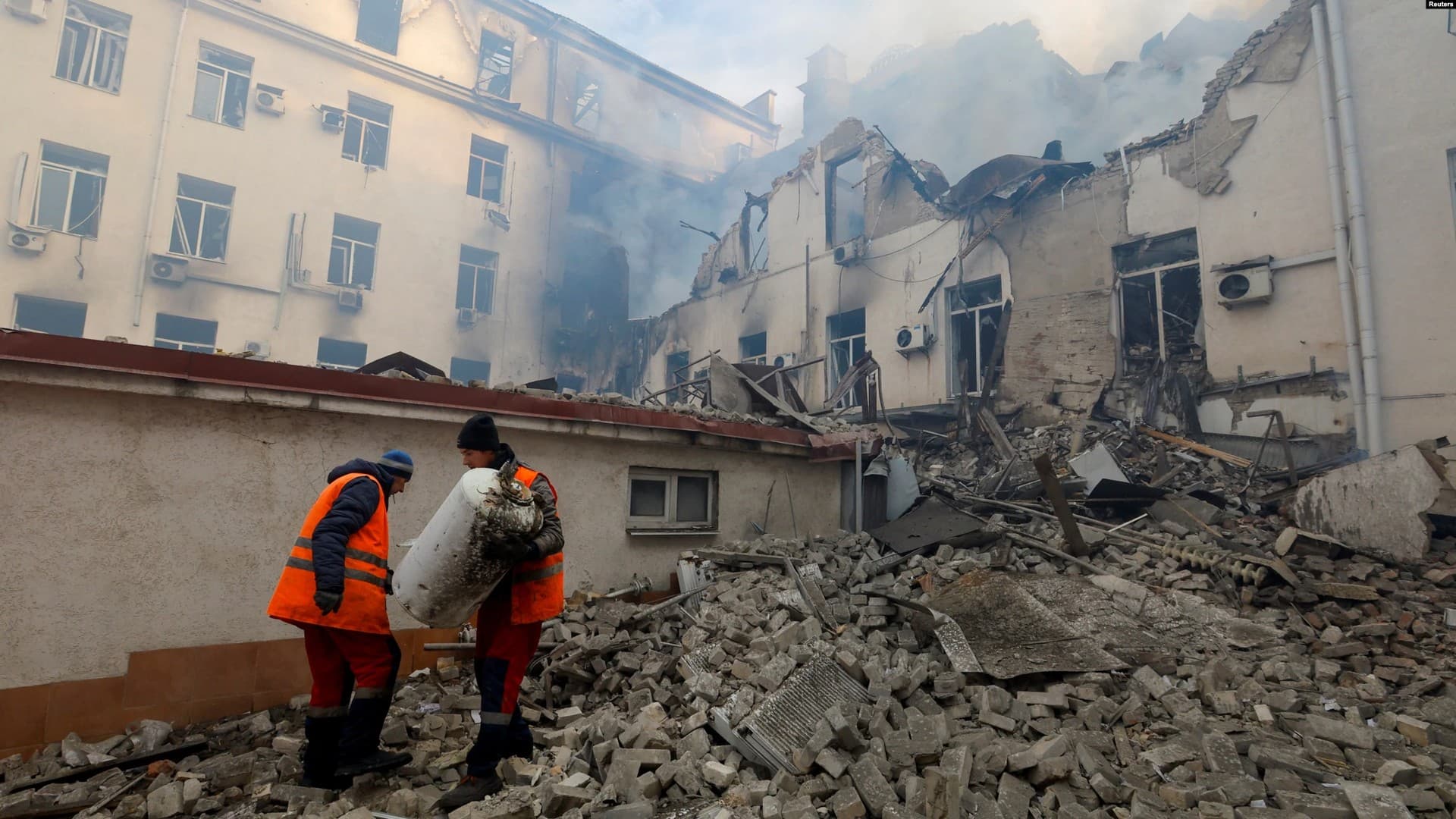 Workers remove debris outside a local railway administration headquarters damaged in shelling in Donetsk