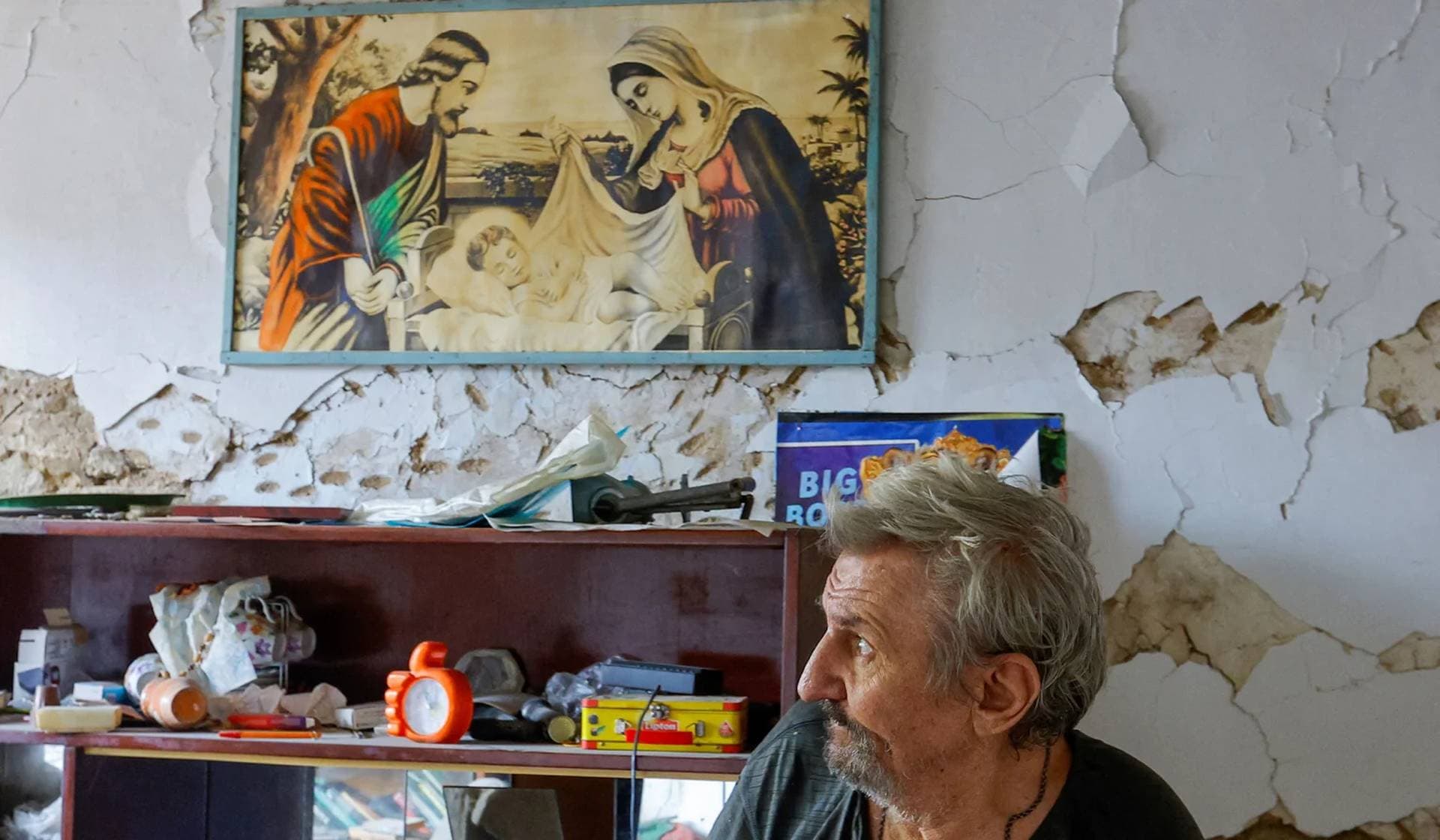 Local resident walks in a room of his house heavily damaged by recent shelling in Donetsk