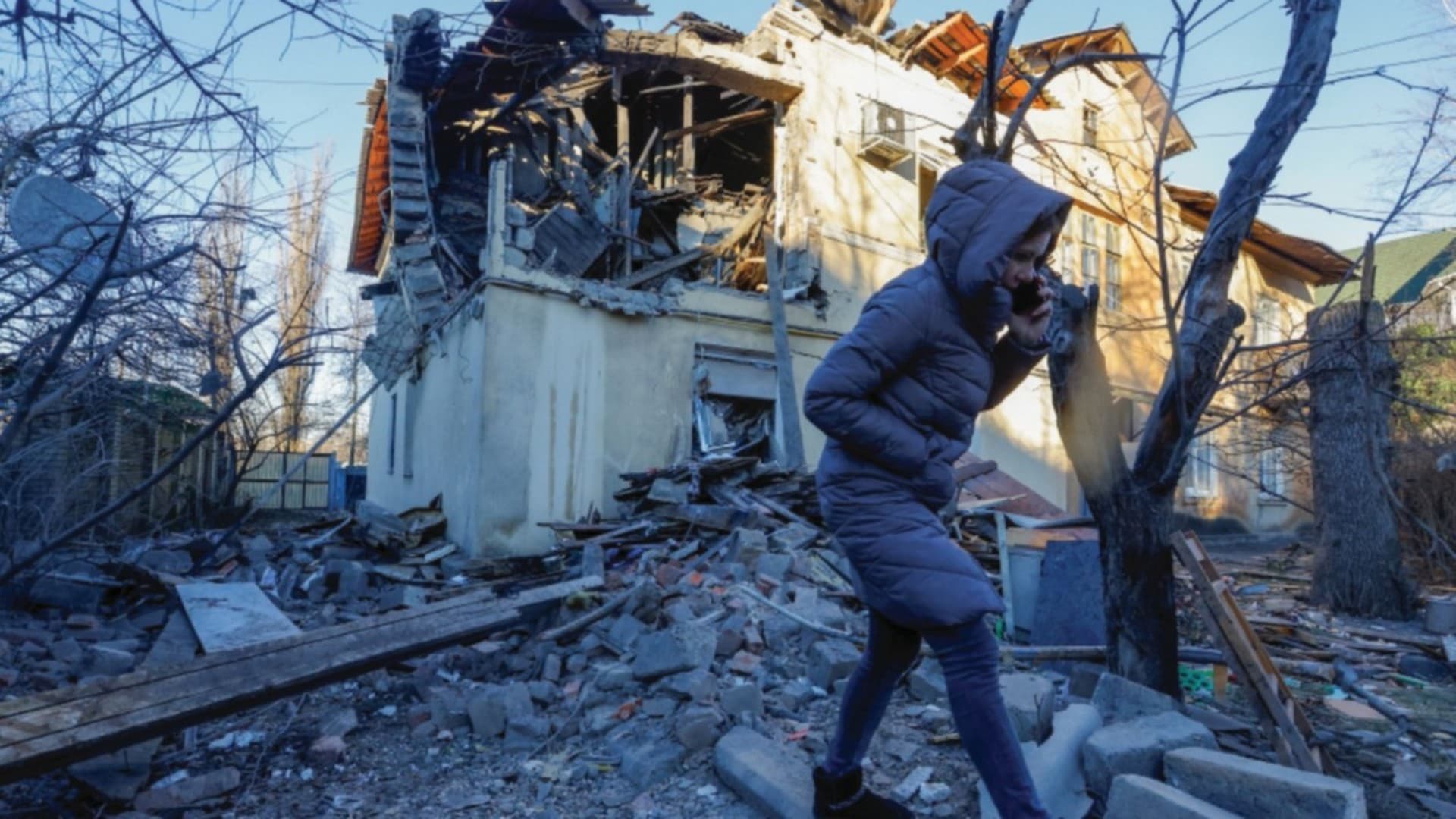 A woman speaks on the phone while walking outside a residential building heavily damaged in recent shelling in Donetsk