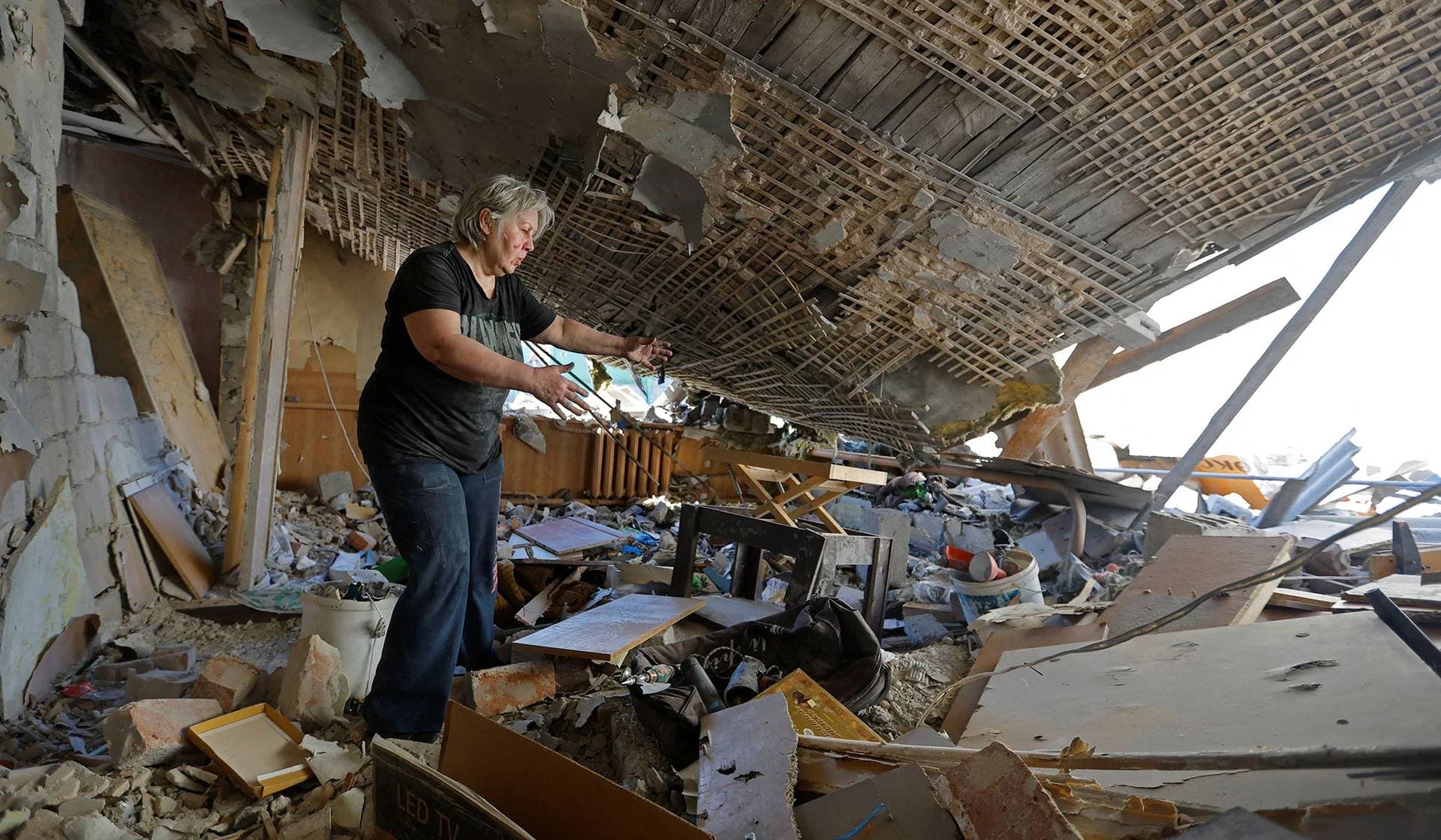 Local resident Natalia Usik, 62, clears the rubble from the ruins of her house destroyed by recent shelling in Donetsk