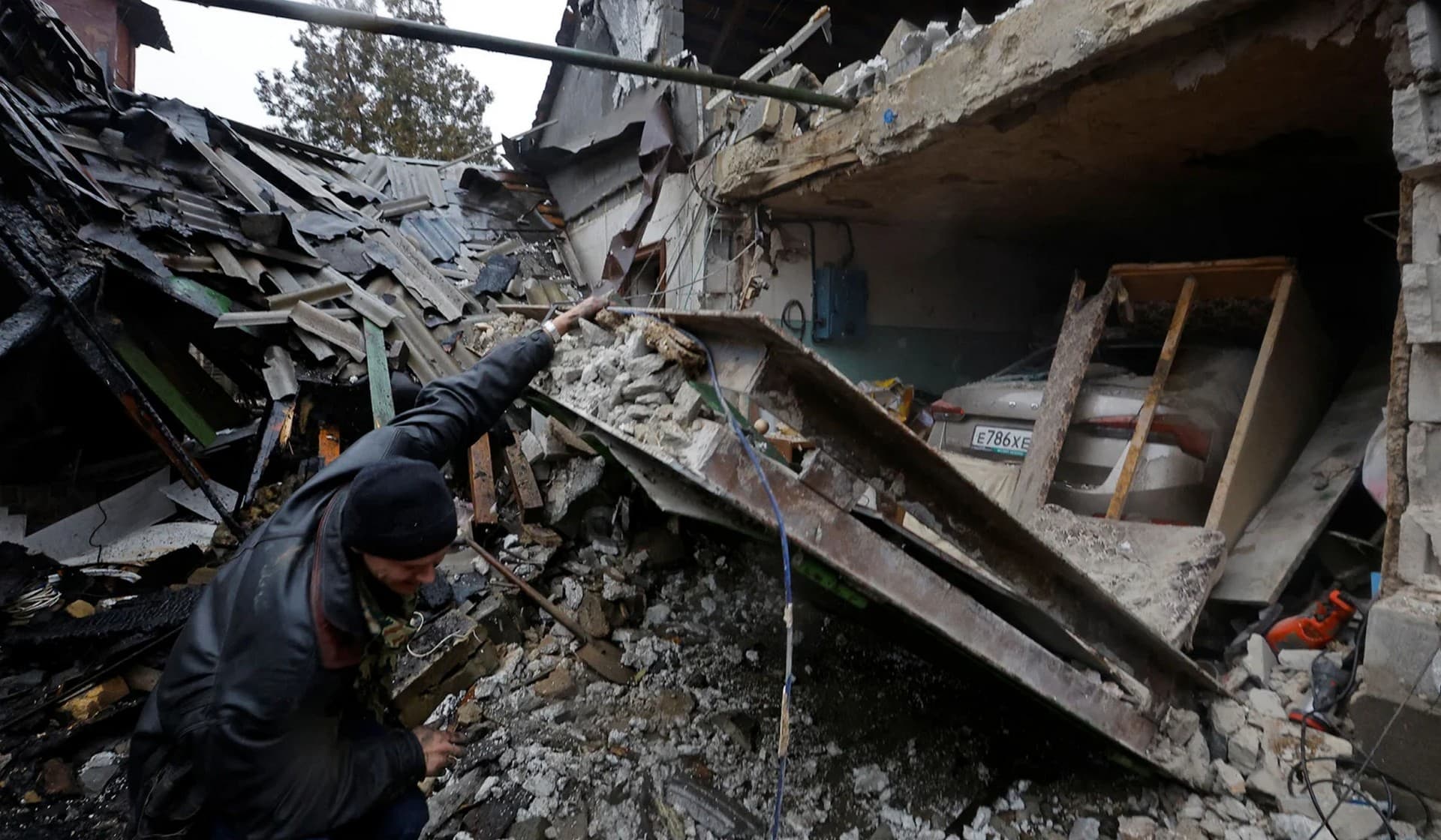 Local resident Amiram stands next to his friend's house that was destroyed by recent shelling in Donetsk