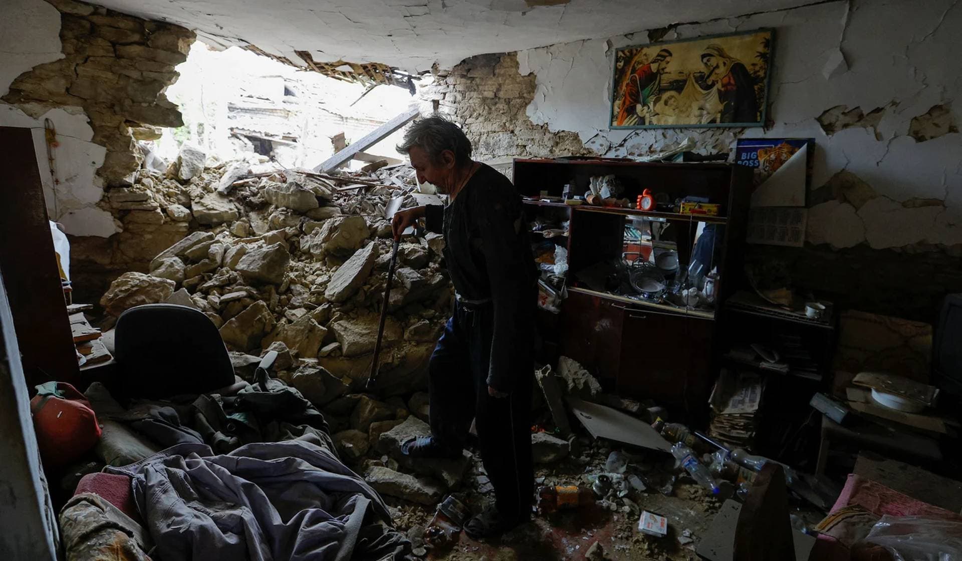 Local resident walks in a room of his house heavily damaged by recent shelling in Donetsk