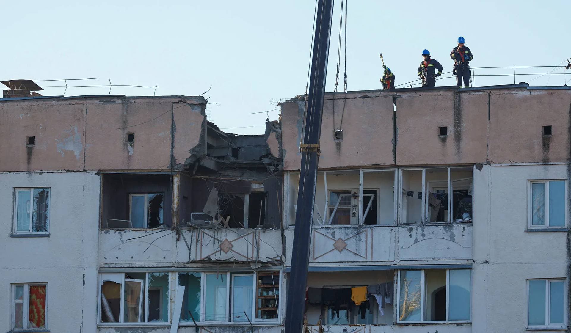 Rescuers work on a roof of an apartment building damaged during a Russian drone strike in the town of Hlevakha