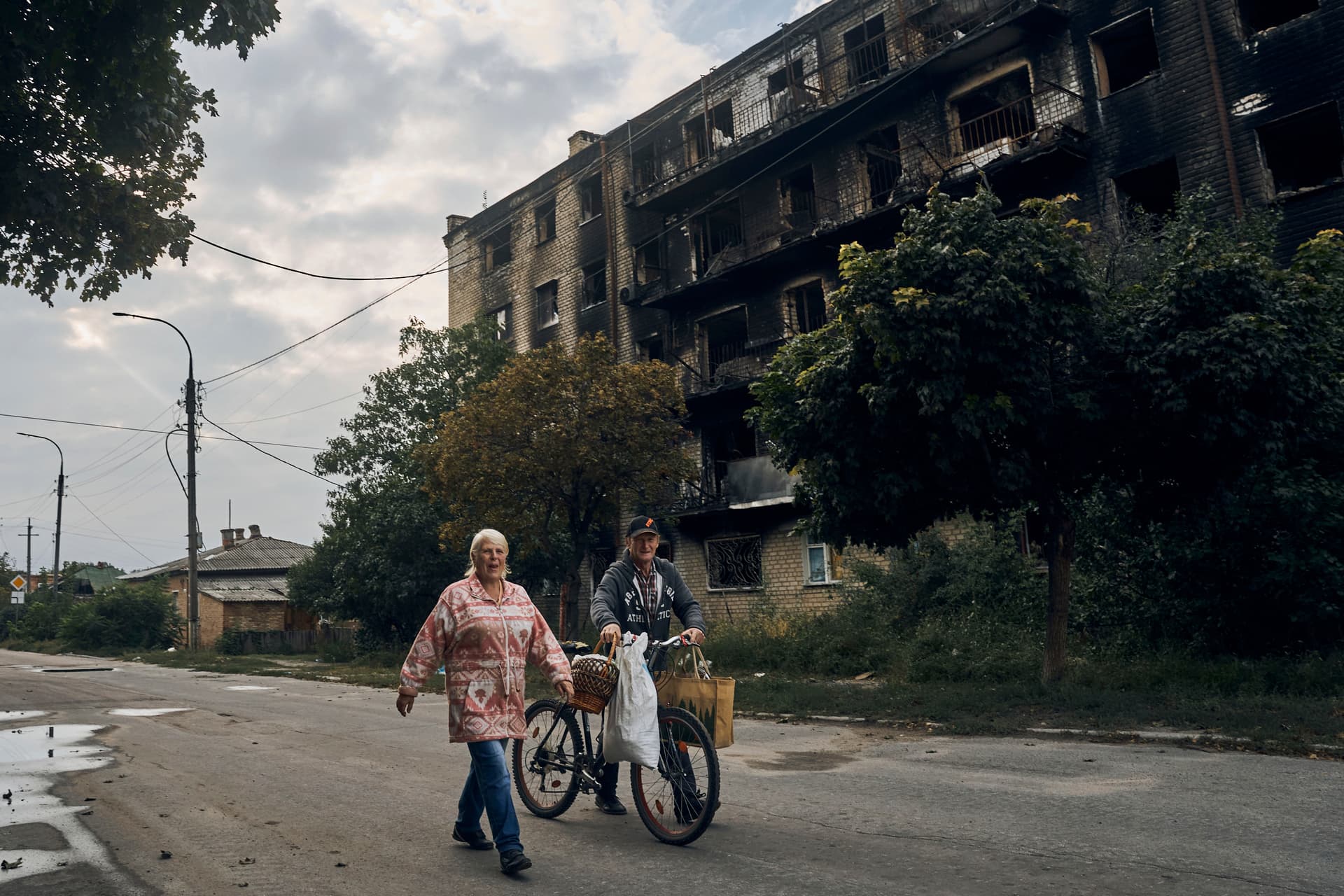 Residents pass by a burnt building in the center of the freed town of Izium