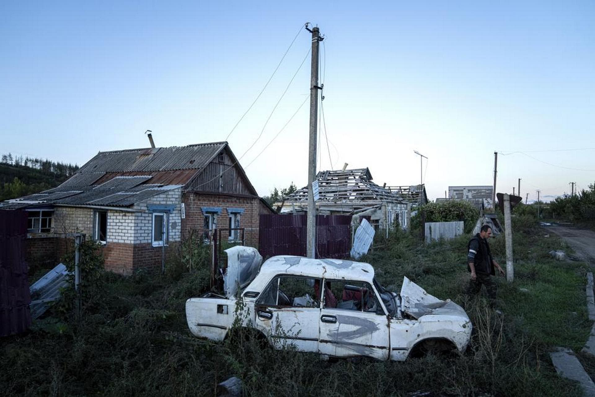 A man walks in front of destroyed car in the recently retaken area of Kamyanka