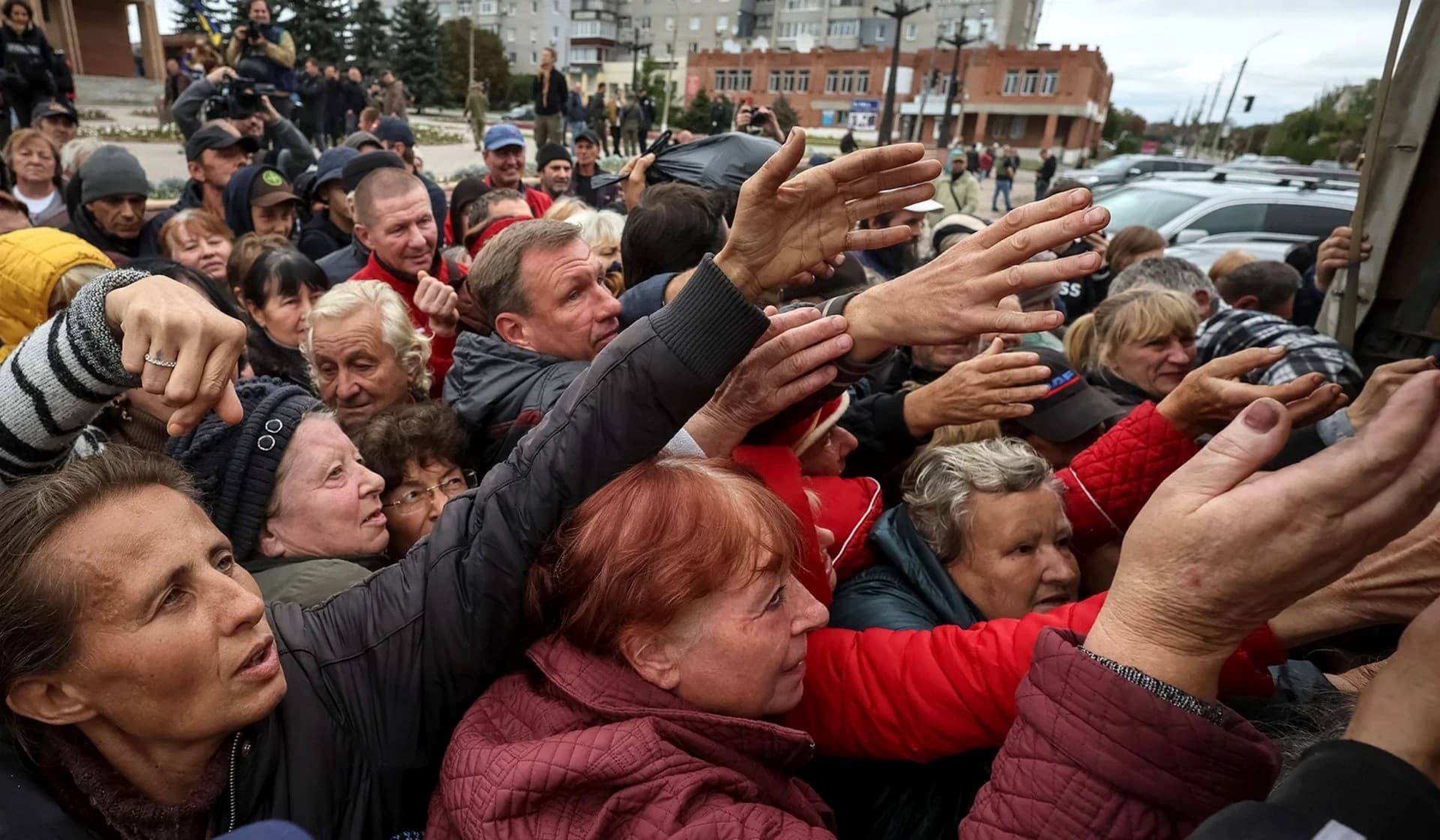 Local residents crowd near a car distributing humanitarian aid in the town of Balakliia