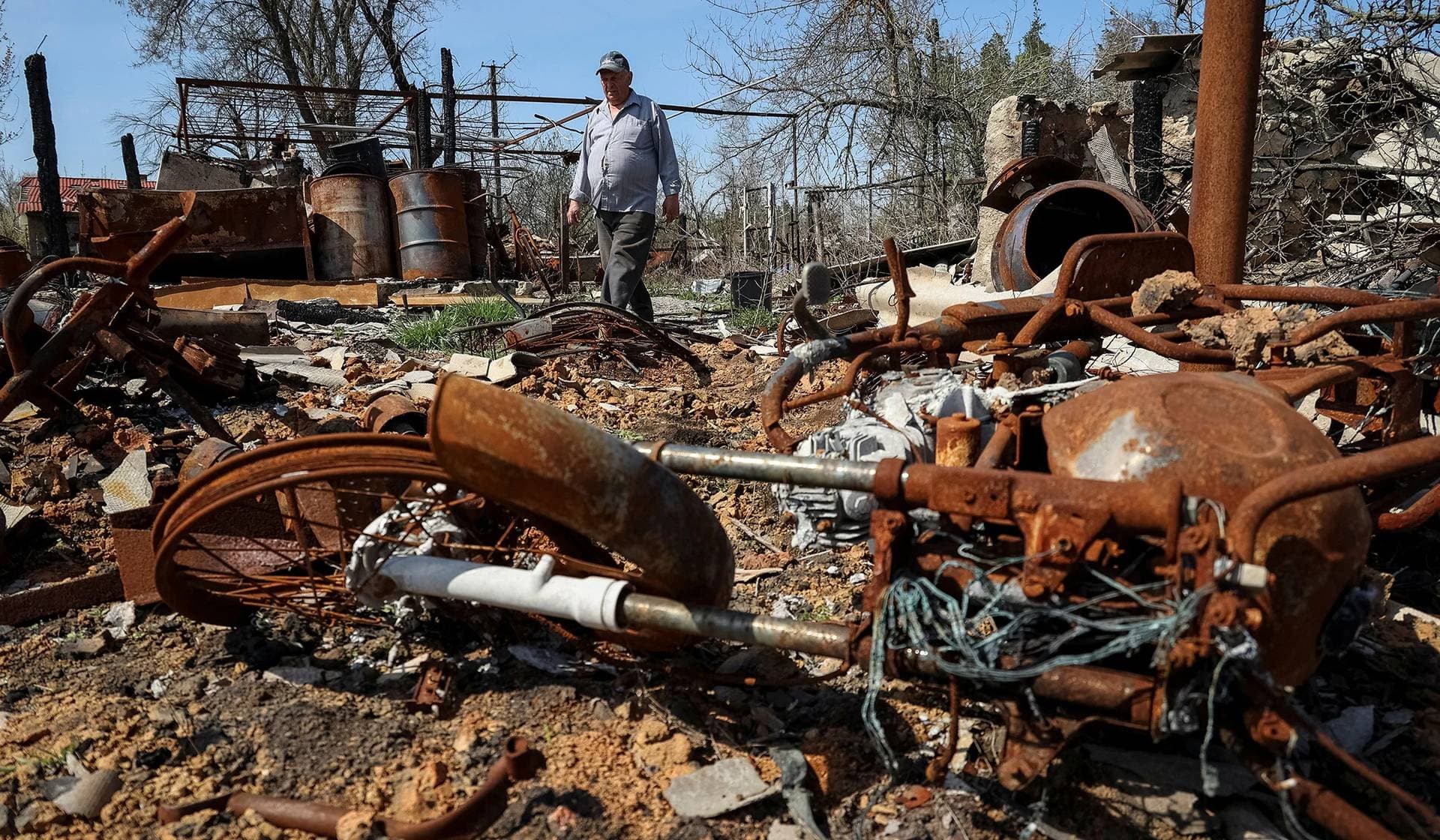 Local resident stands among the remains of his house destroyed in the village of Studenok