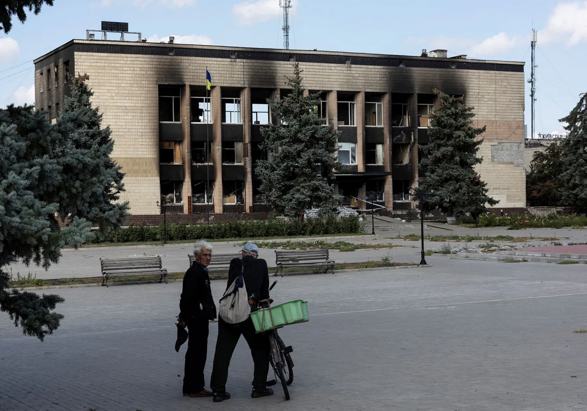 Local residents stand in front of a destroyed building in the town of Izium