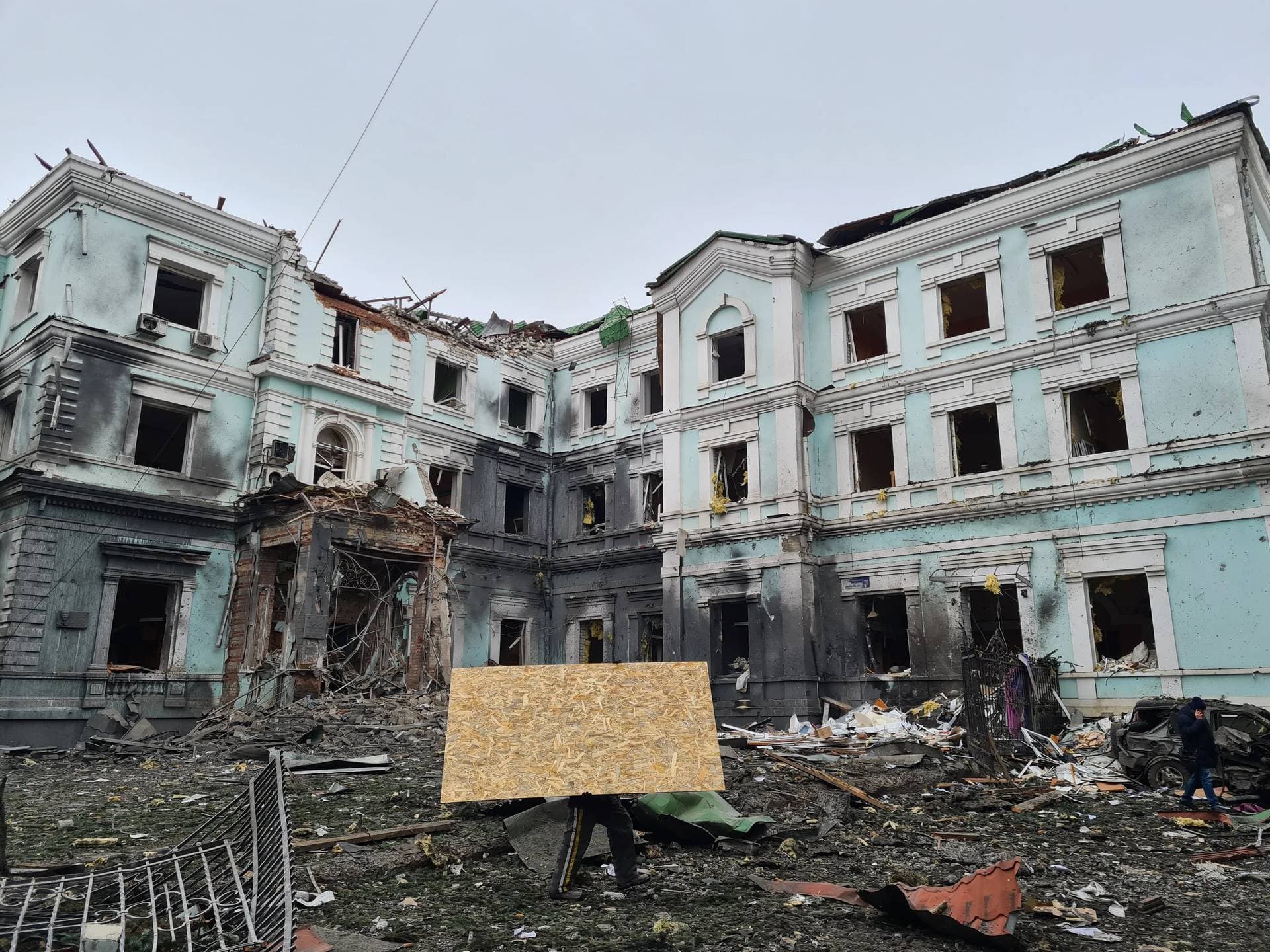 A man carries a wooden board to replace broken glass in a building in central Kharkiv damaged by Russian missiles