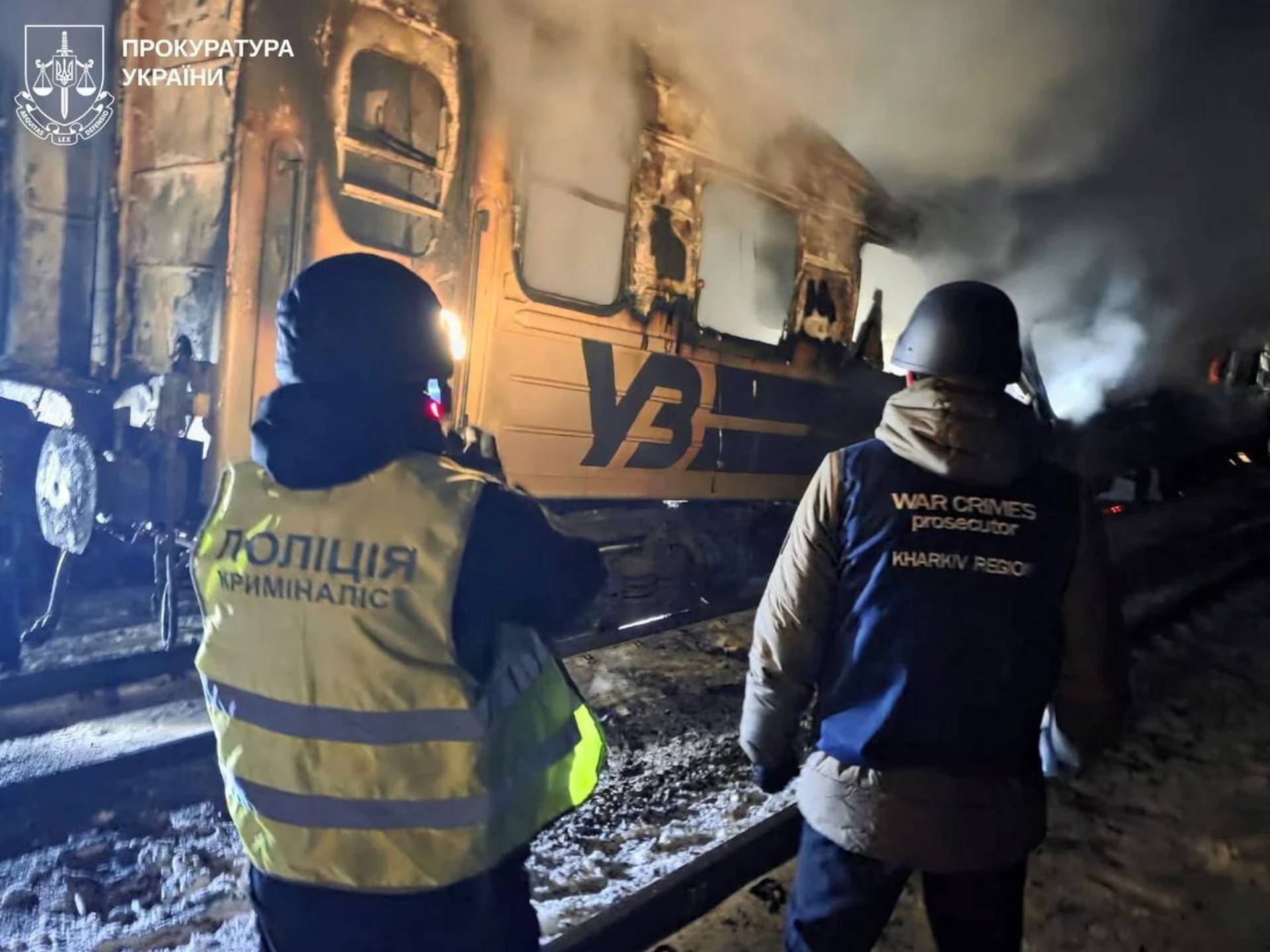 A war crime prosecutor and a police officer work next to a passenger train hit by a Russian drone strike in Kharkiv Region