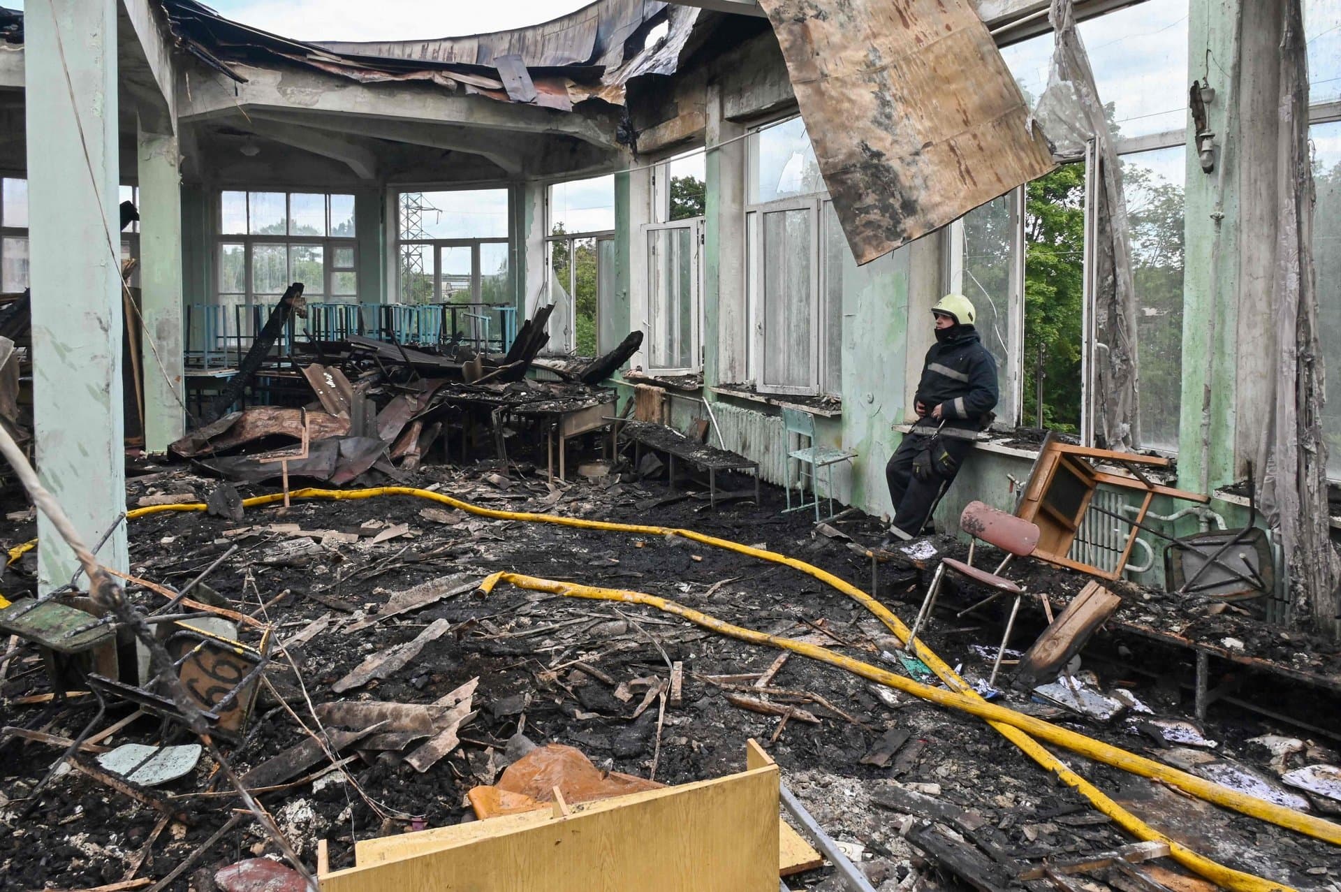 A firefighter takes rest after extinguishing a fire in the building of a vocational school after a missile strike in the Ukrainian city of Kharkiv