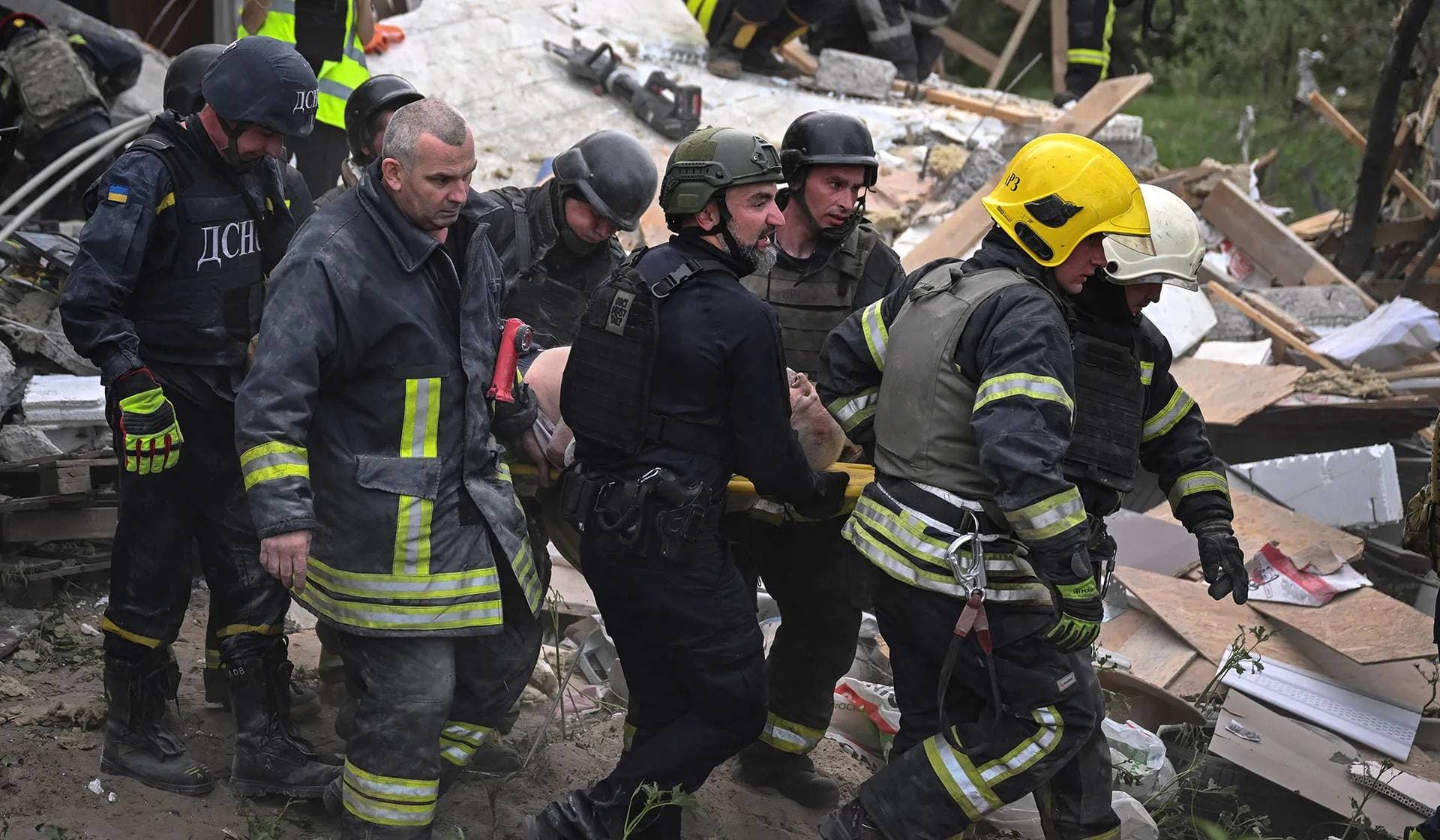 Rescue members carry a wounded local resident at a site of a private house destroyed during a Russian air strike in Kharkiv