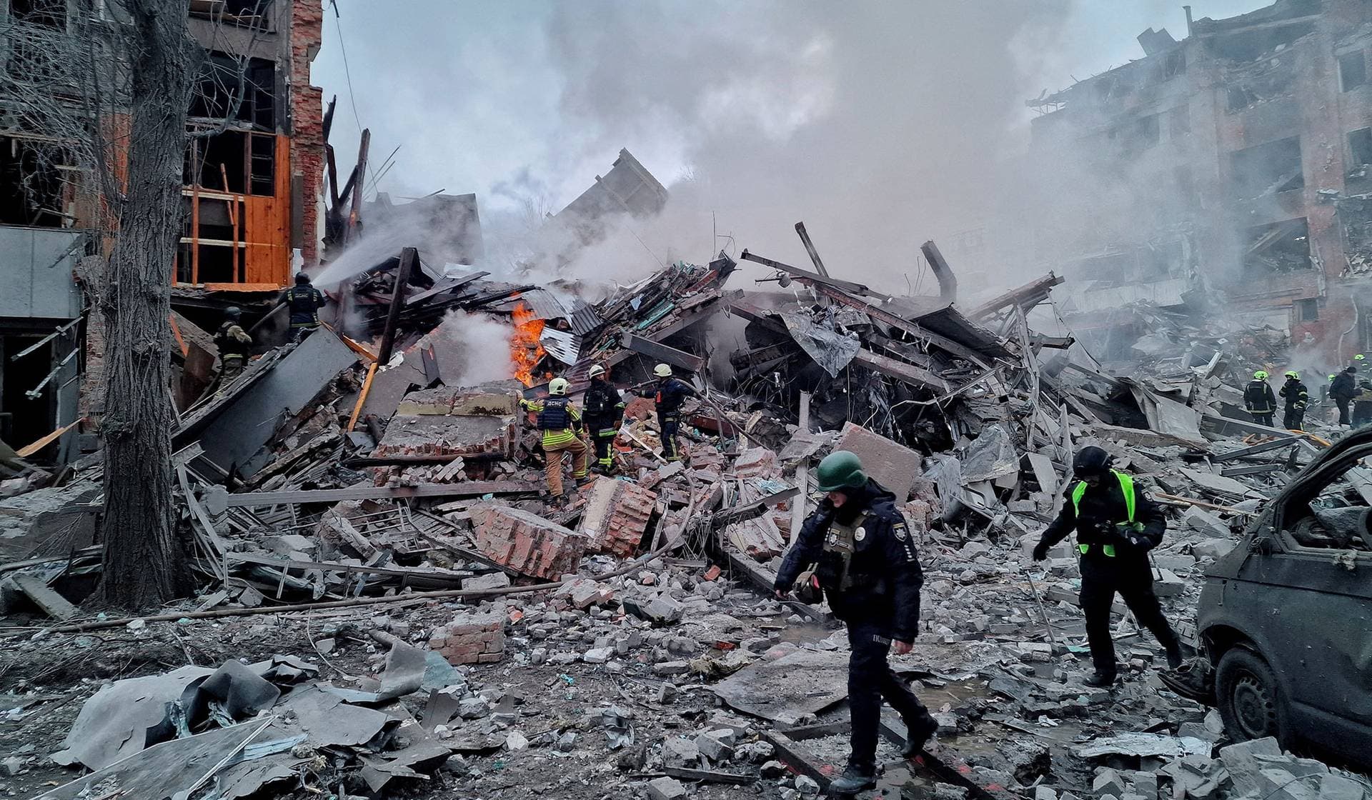 Firefighters work at the site of an apartment building hit by a Russian air strike in Kharkiv