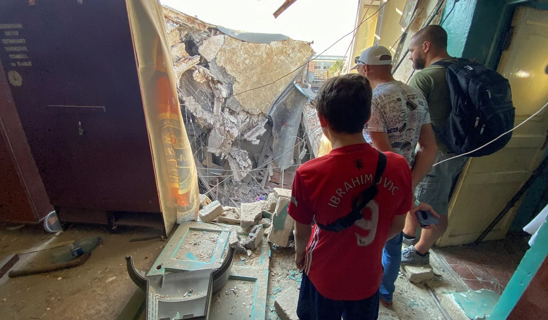 Local residents look at debris of a residential block of a tram depot hit by a Russian missile strike in Kharkiv